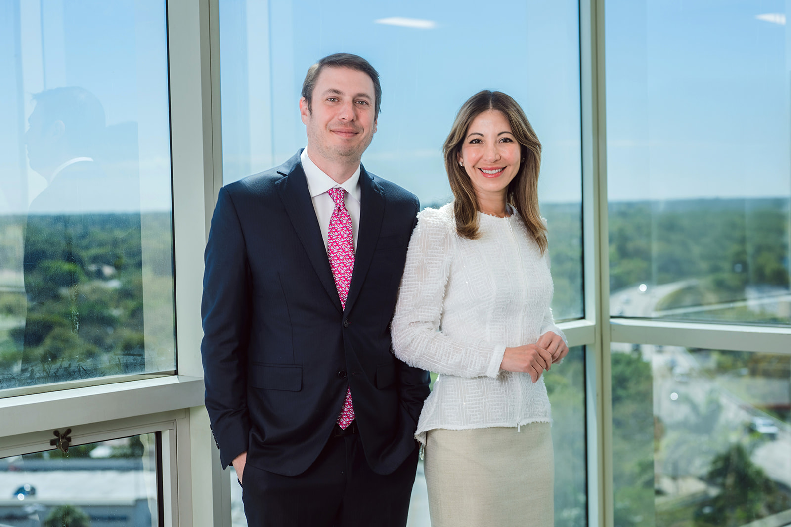 Professional couple posing by office windowsRetry