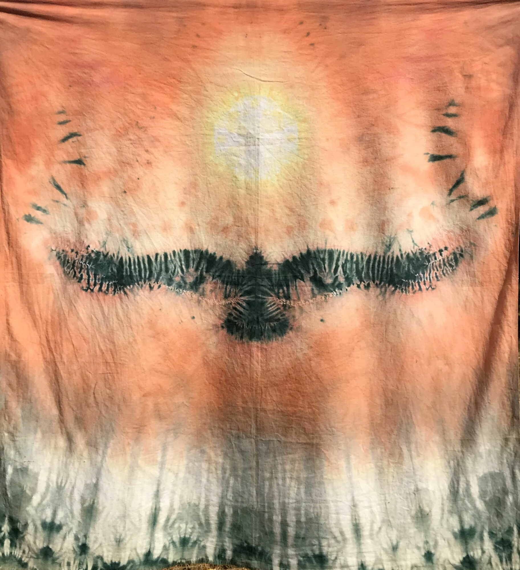 T-shirt with a black bird silhouette, a cross with a halo, and abstract patterns on a reddish background.