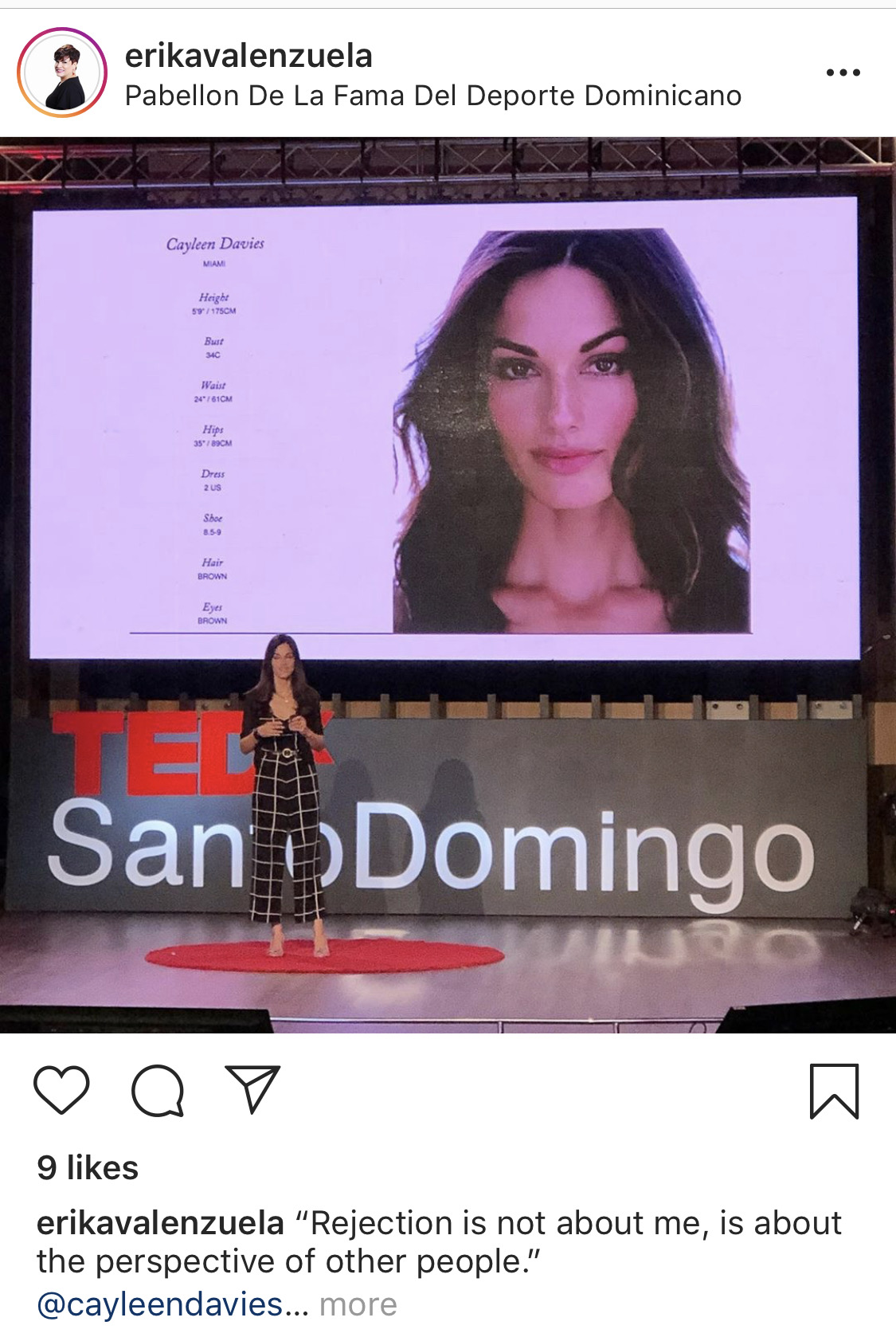 Woman standing on stage in front of a large screen displaying a woman's portrait and text, TEDx logo visible.