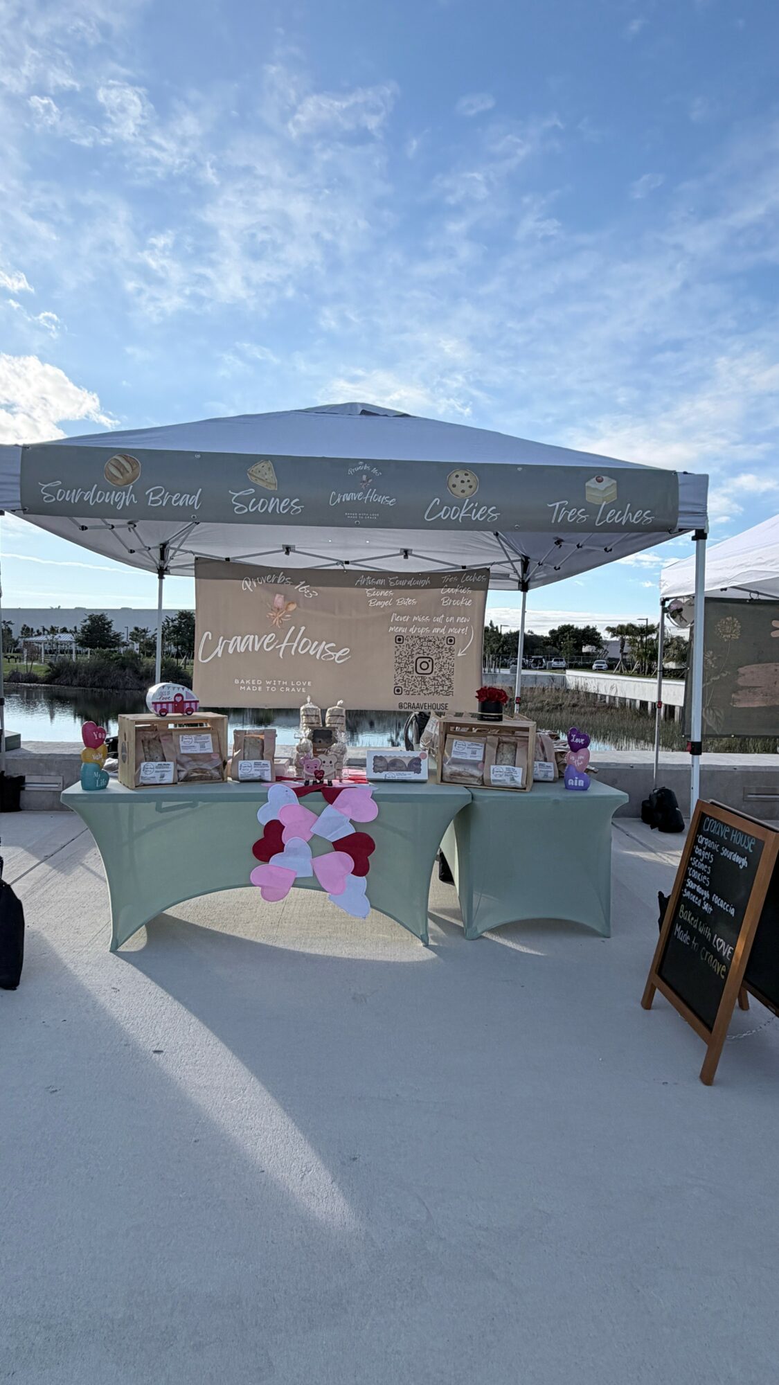 Outdoor event booth with tables, decorations, and a canopy under a blue sky with clouds.