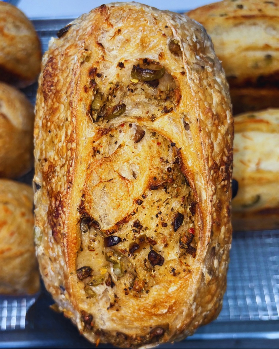 Close-up of a baked pastry with a golden, flaky crust and visible dark filling or ingredients inside.