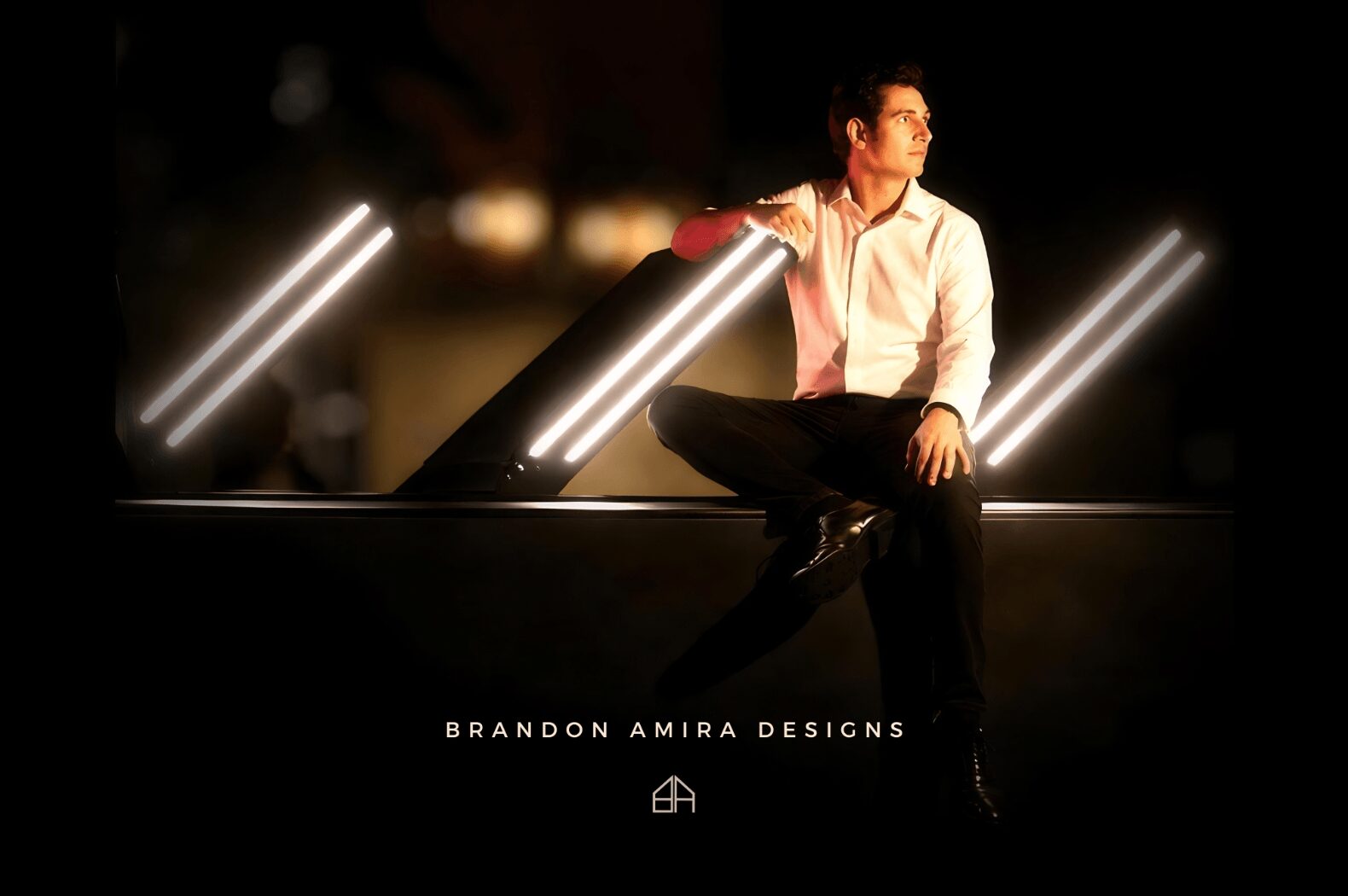 Person sitting on a ledge with illuminated light fixtures around, nighttime setting, Brandon Amira Designs text below.