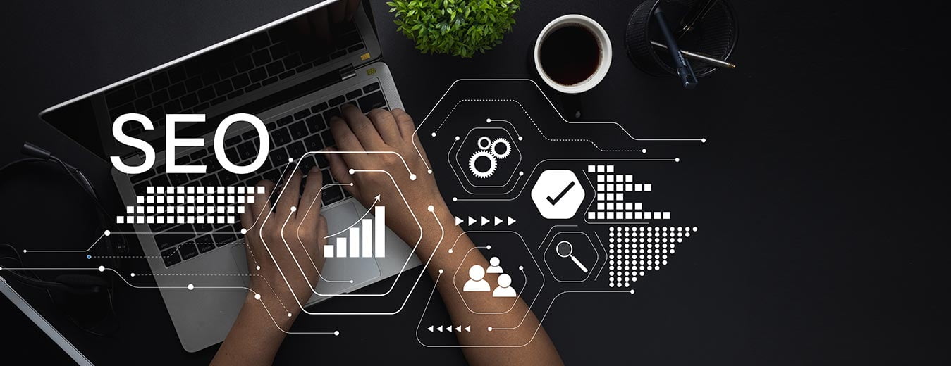Hands on a laptop with SEO-related icons and graphs on a dark background.