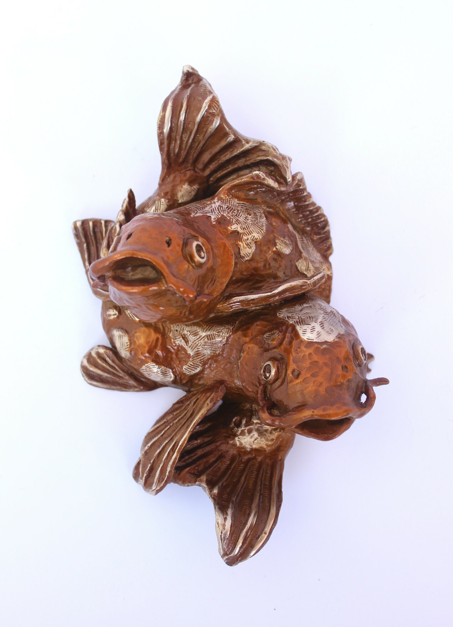 Three fish-shaped ceramic sculptures stacked together, with detailed fins and scales, on a white background.