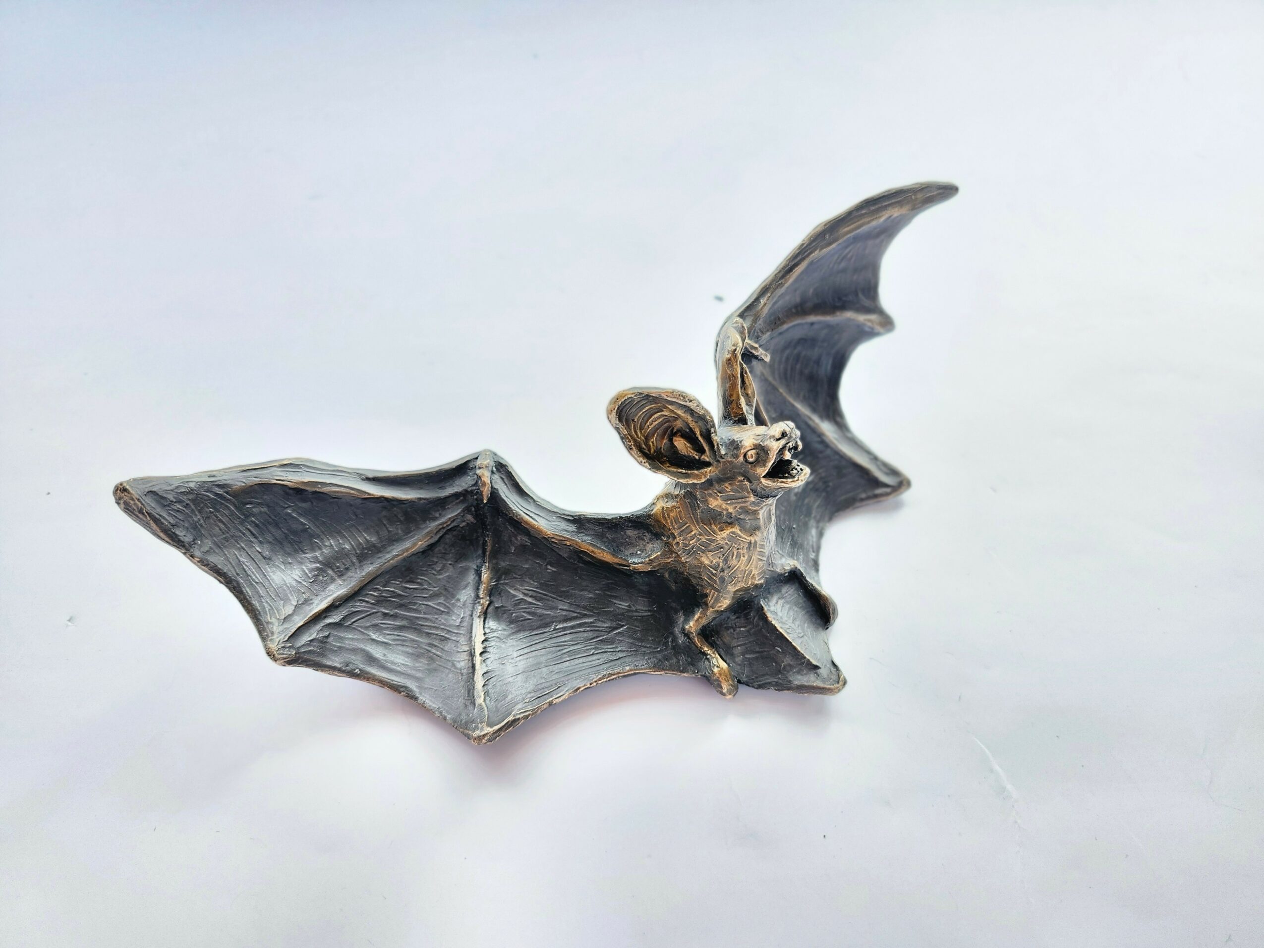 Model of a bat with wings spread, showing detailed features and textured surface.