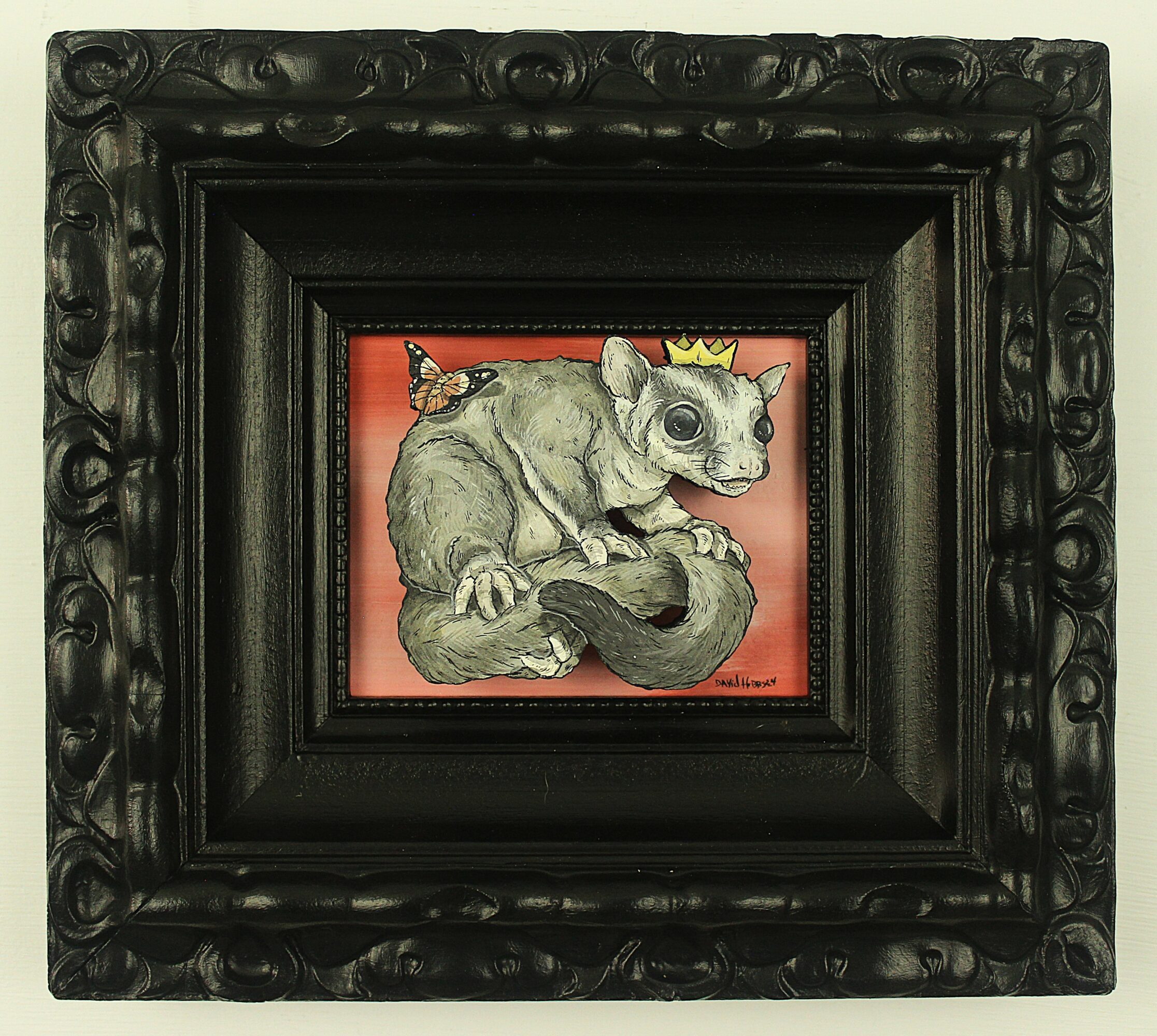 Drawing of a small animal with a crown, sitting on a branch, framed in a black ornate frame.