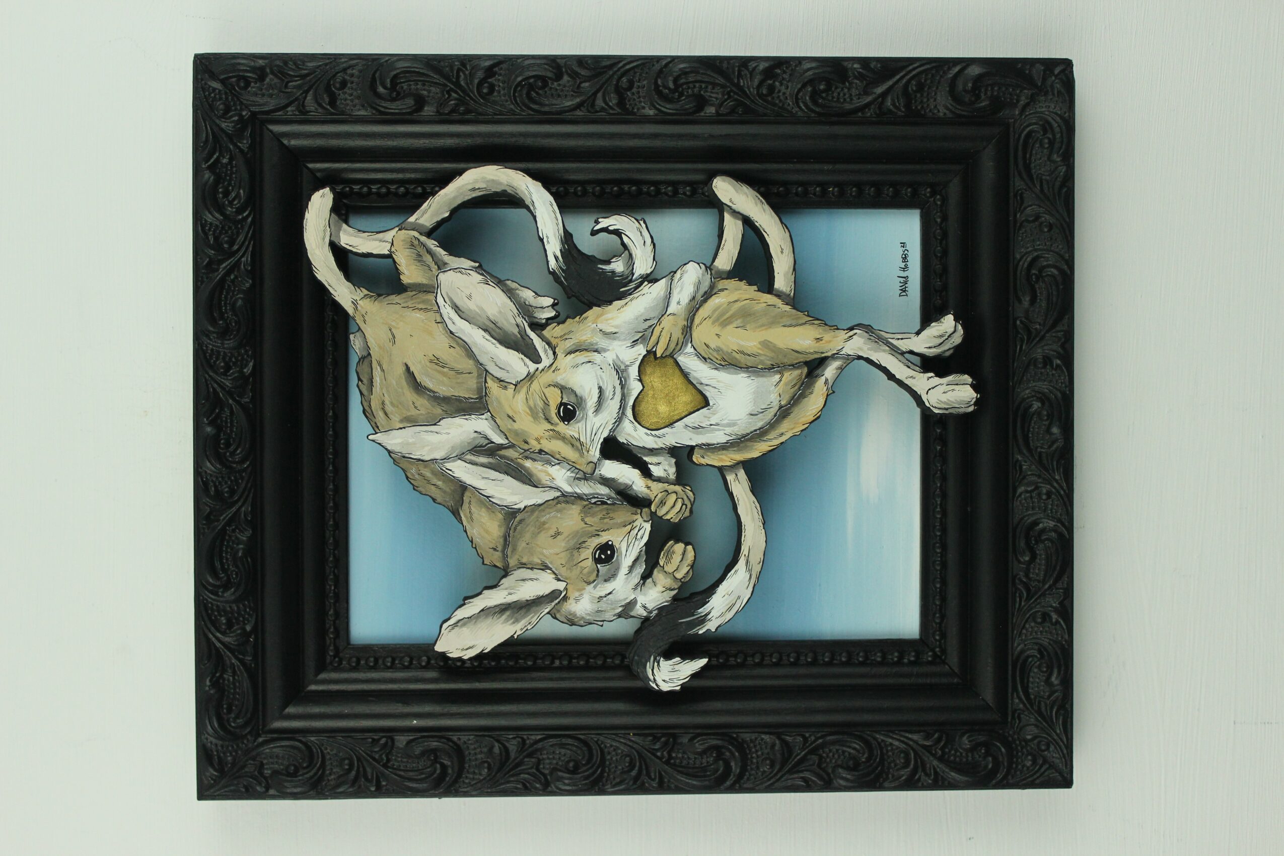 Three rabbits are inside a black ornate picture frame, with a blue background behind them.