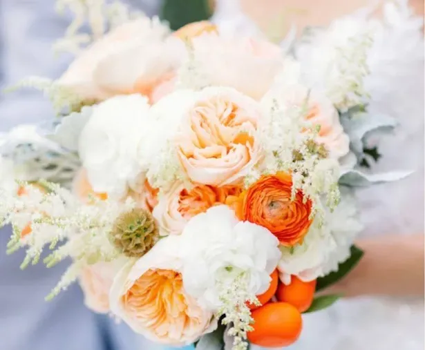 Bouquet of peach, white, and orange flowers with greenery and white accents.