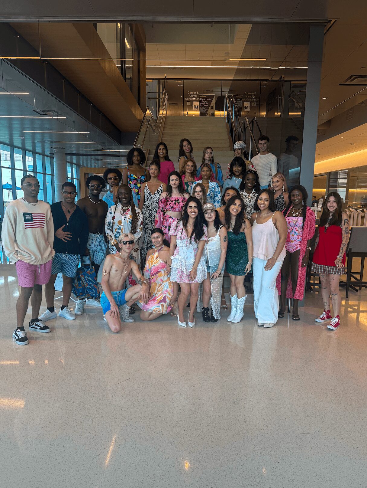 Group of diverse women and children standing in a modern indoor space with glass walls and stairs.