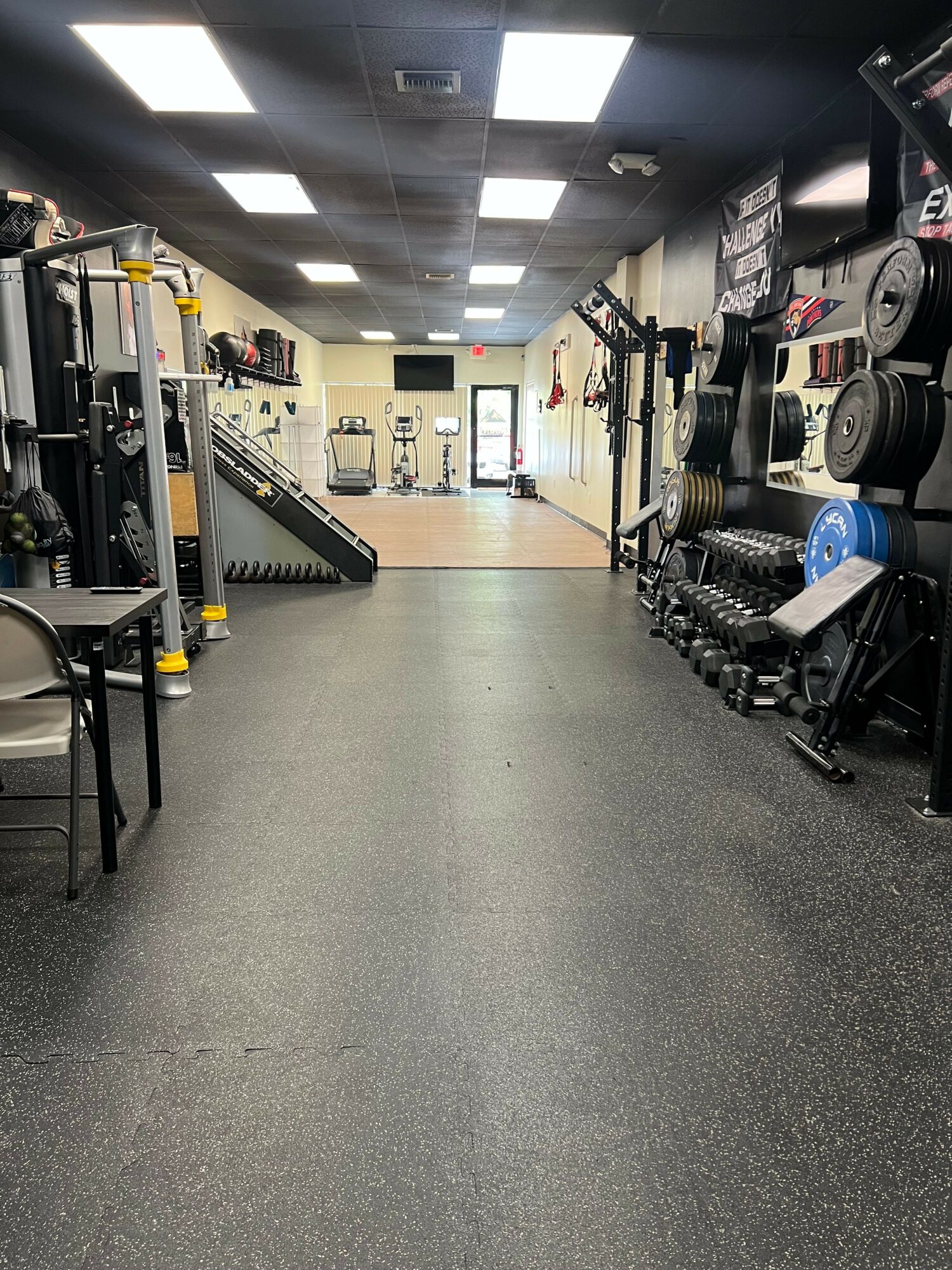 Empty gym with workout equipment, weights, and a large open space in the center.