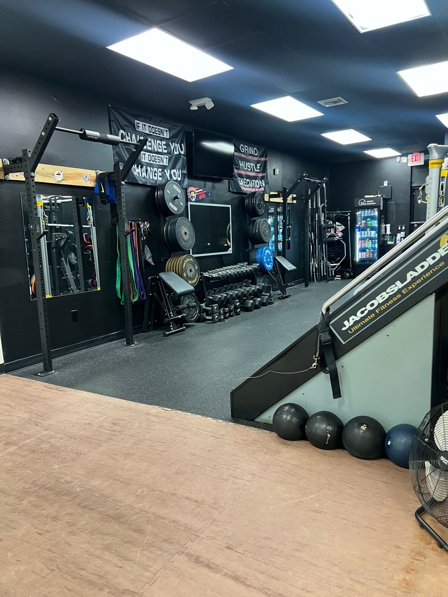 Gym with weight racks, medicine balls, and exercise equipment in a well-lit space.