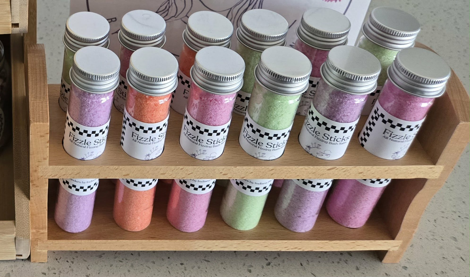 Two shelves with small jars of paint in various colors, arranged in rows on a wooden display stand.