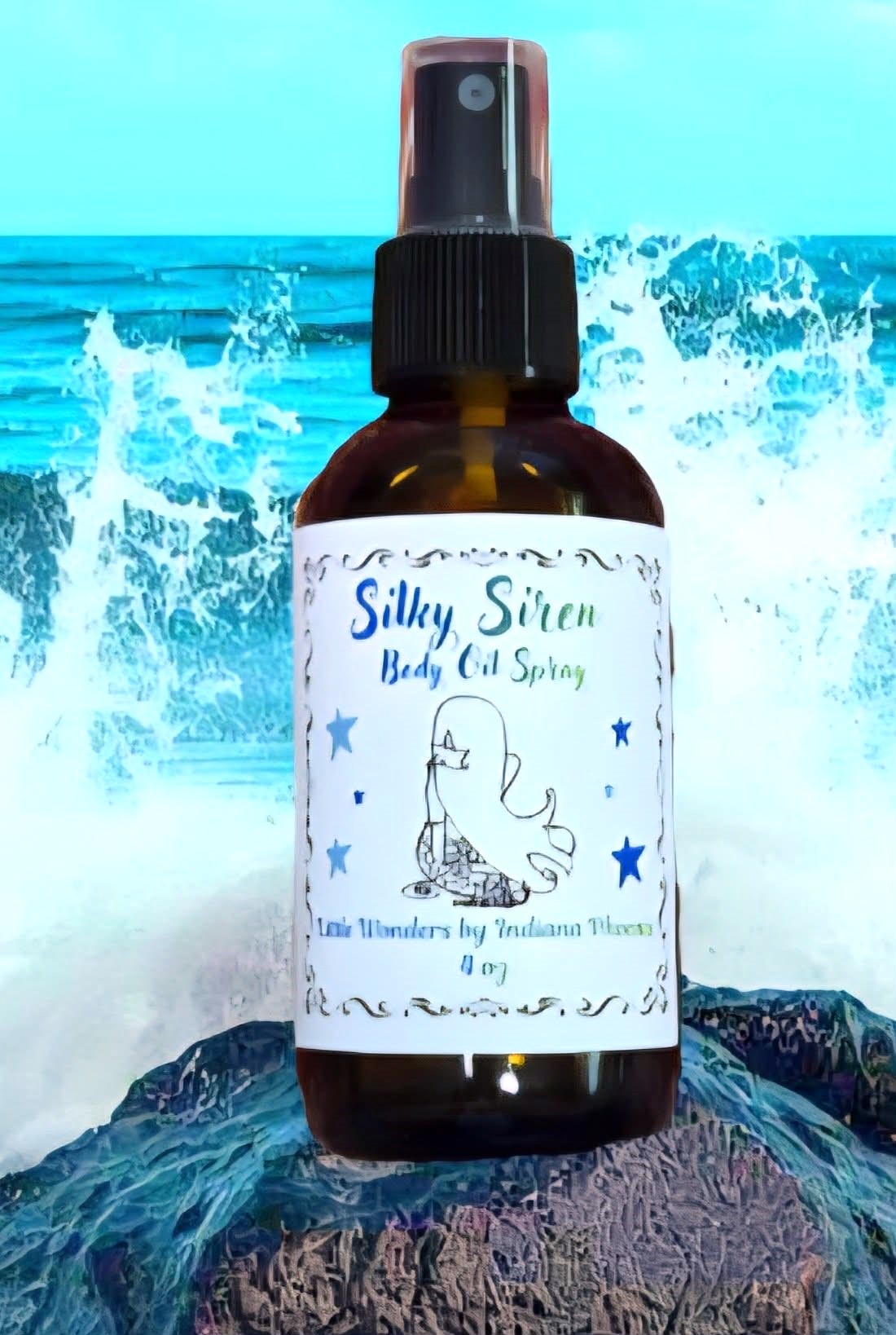 Bottle with a unicorn illustration and text, placed on rocks with ocean waves in background.