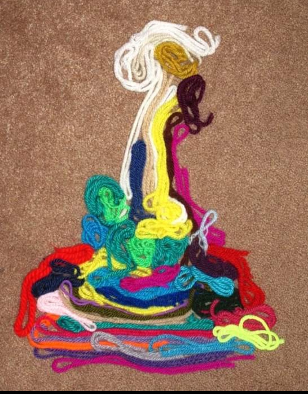 Colorful embroidered abstract figures with flowing lines and vibrant colors on a brown background.