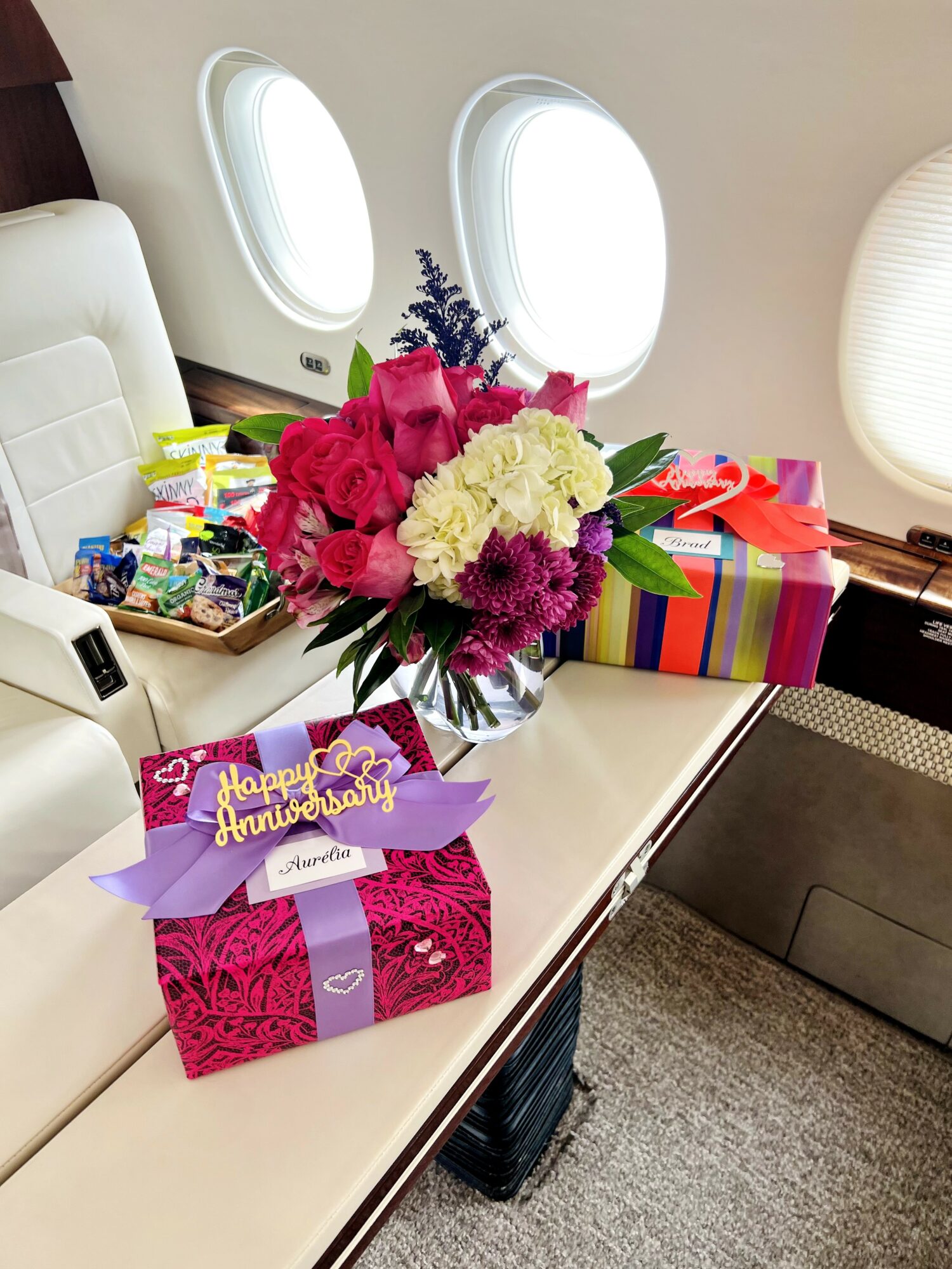 Bouquet of pink, white, and purple flowers on table with colorful wrapped gift boxes and a birthday card.
