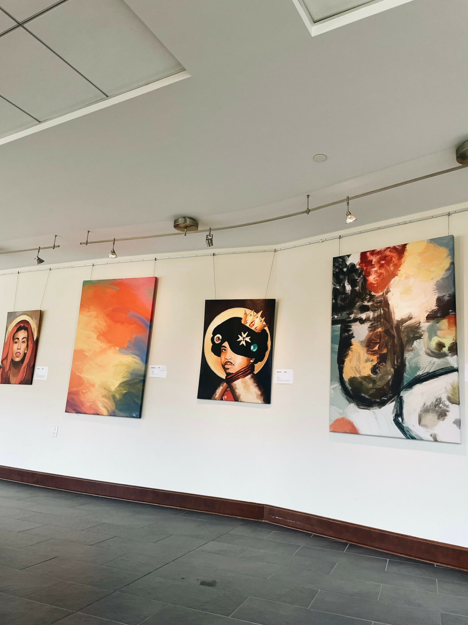 Gallery wall with five colorful paintings, including a portrait, abstract art, and a girl with a hat.