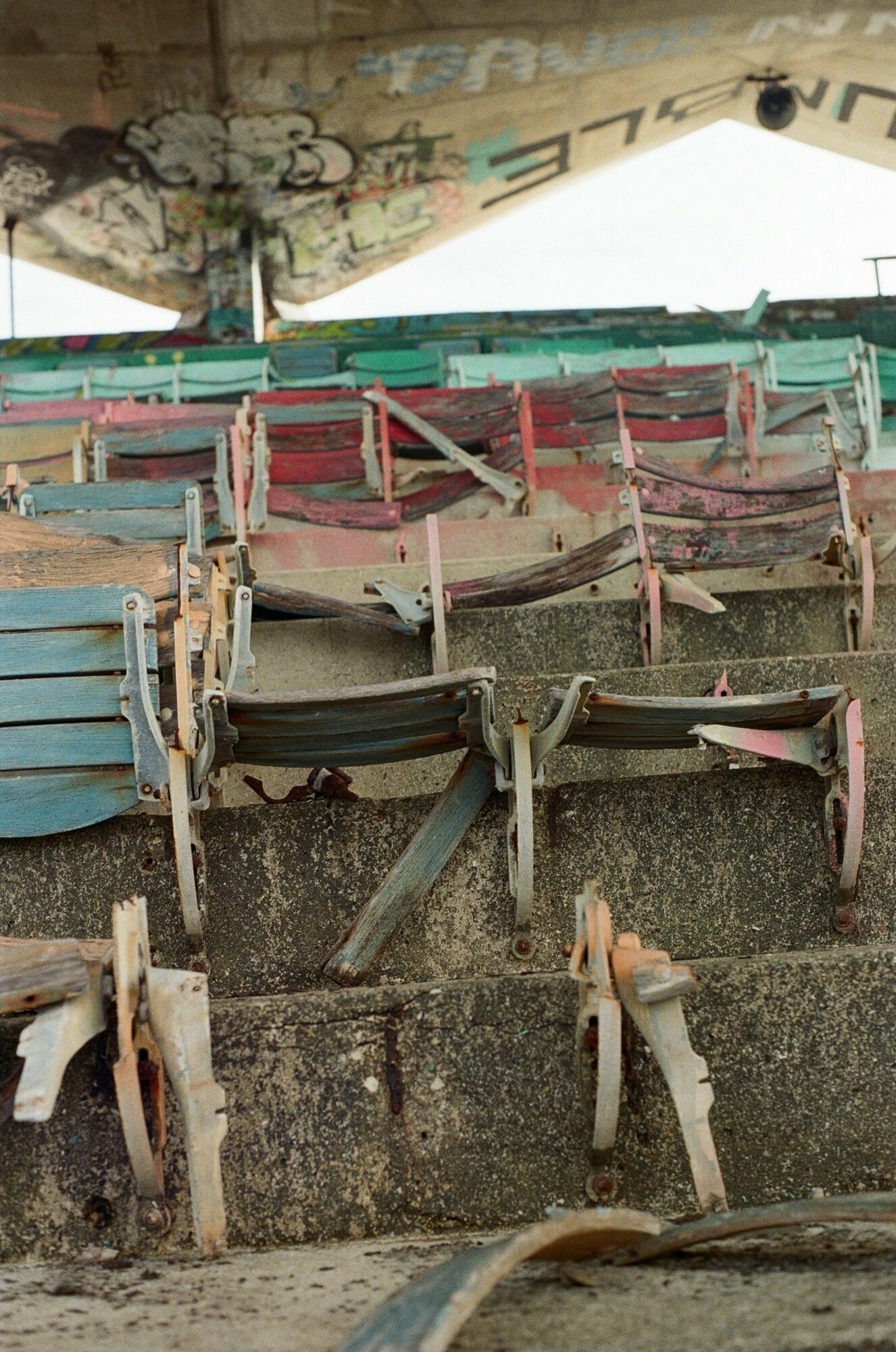 Multiple abandoned boats stacked on concrete steps, some with peeling paint and rust, in a deteriorated environment.