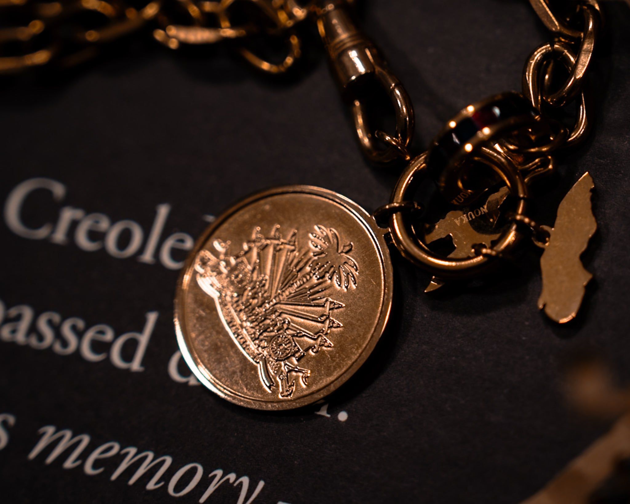 Close-up of a gold coin attached to a chain with a torn paper in the background.