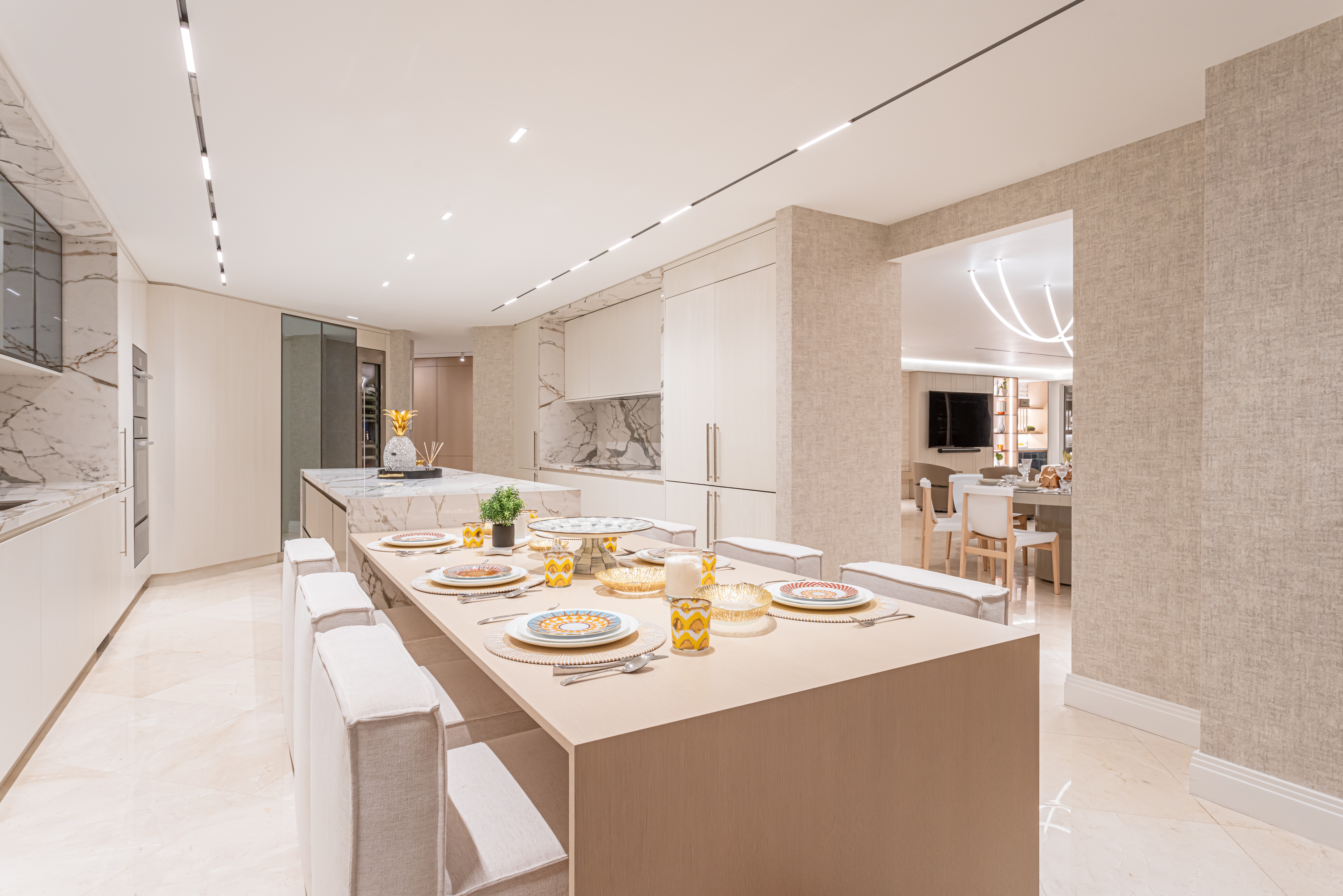 Modern kitchen with a large island, white countertops, and dining area with table set for four people.