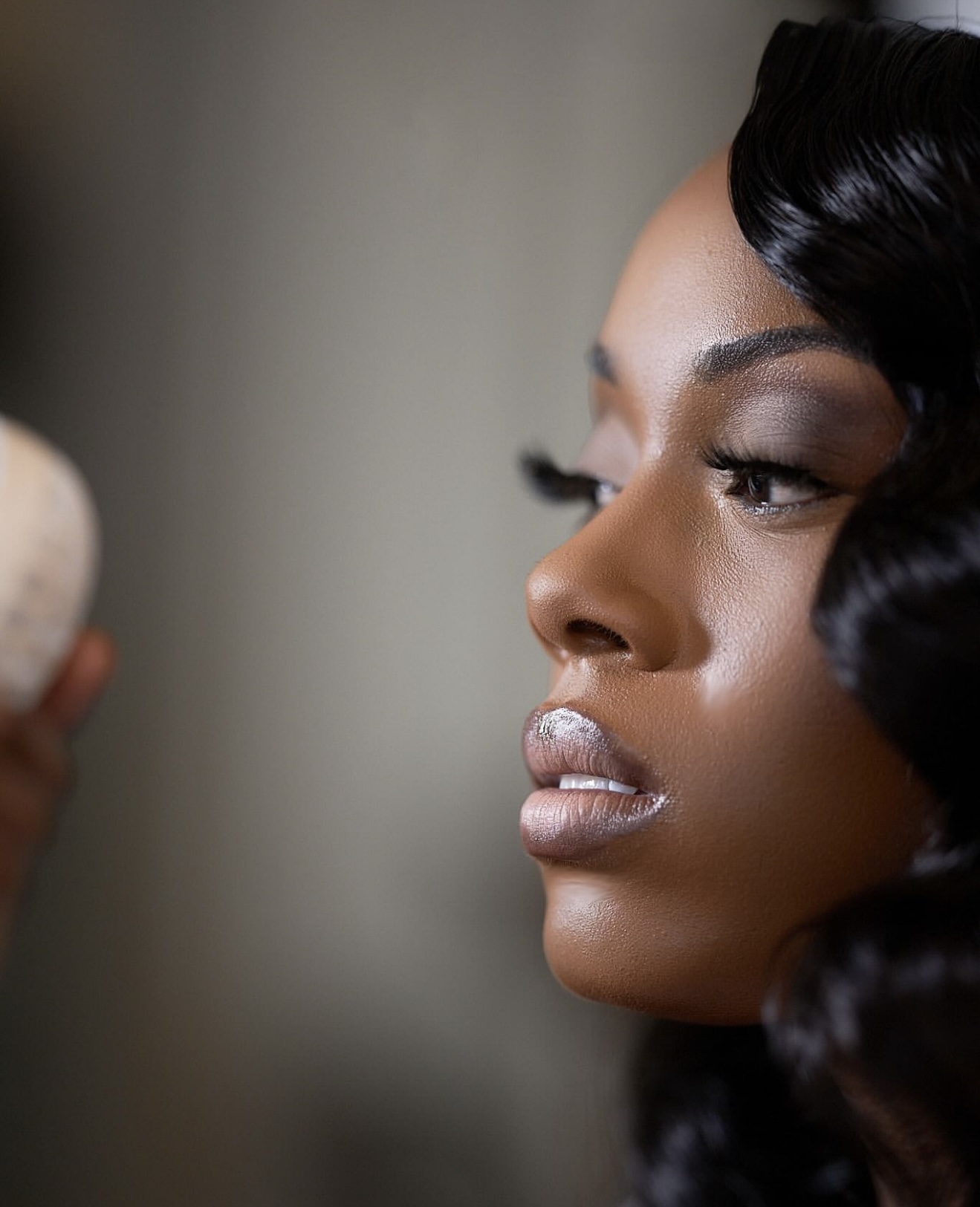 Close-up of a woman with styled hair and makeup, looking to the side.