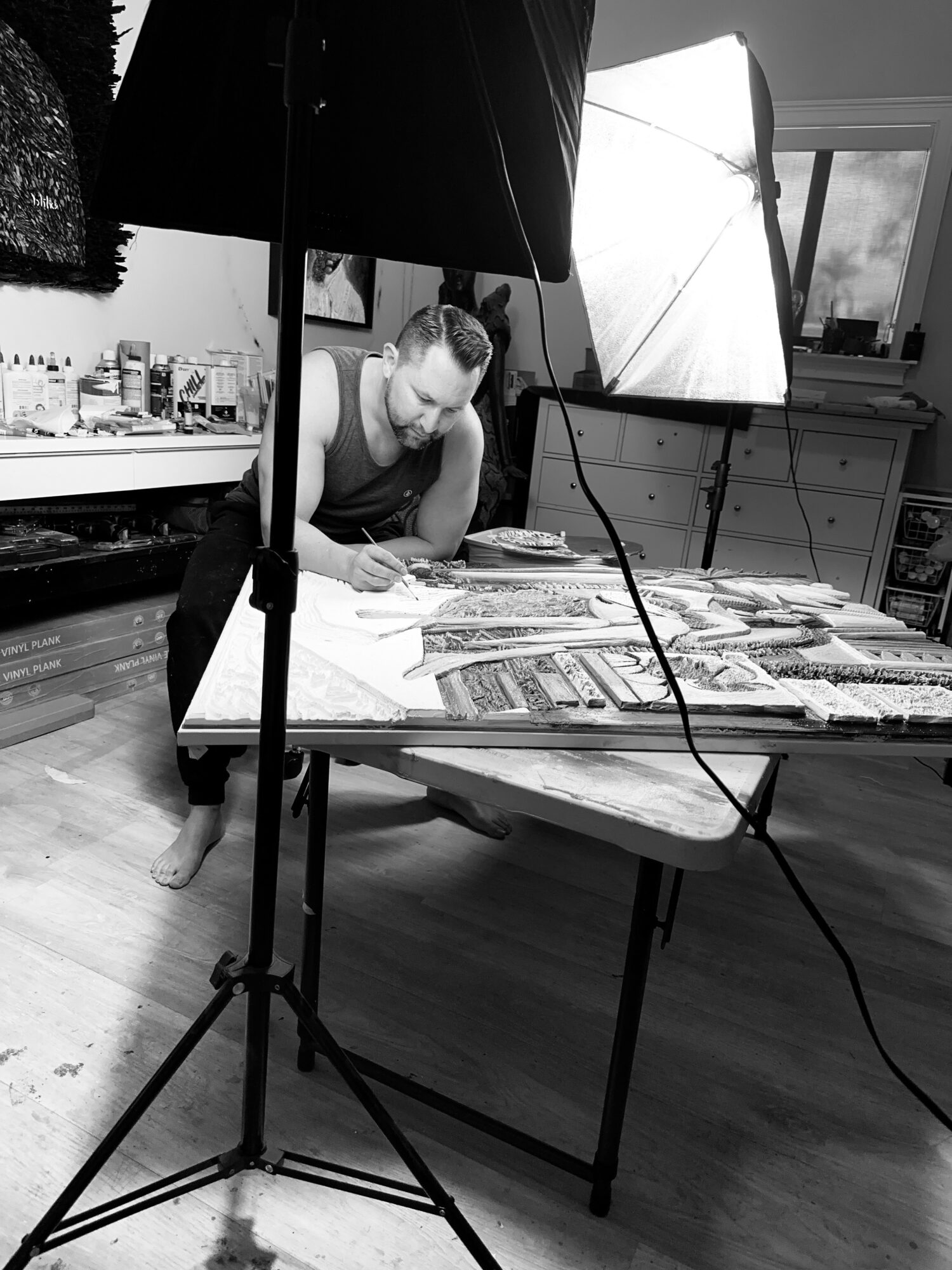 Person working at a table with magazines, surrounded by photography equipment and a window with a view outside.