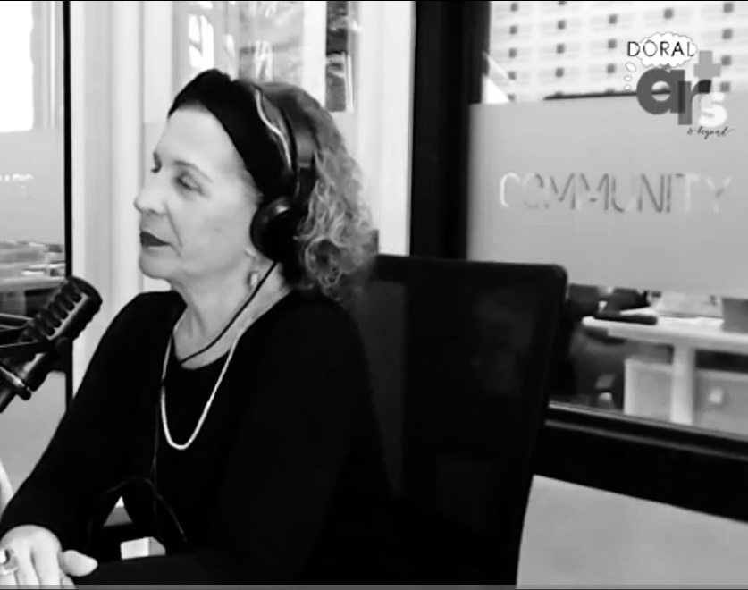 Woman wearing headphones speaking into a microphone in a radio studio.