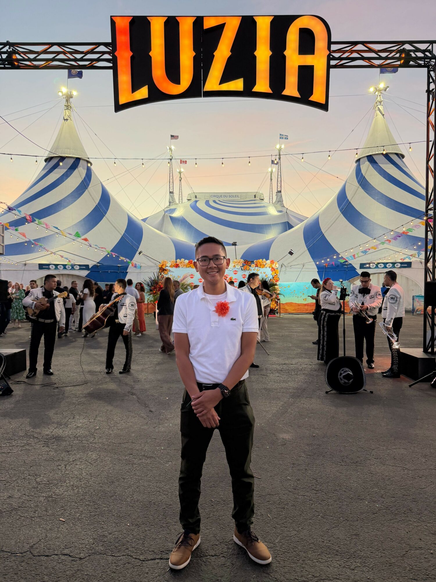 Person standing in front of a circus tent with a large illuminated sign reading 'Luzia'.
