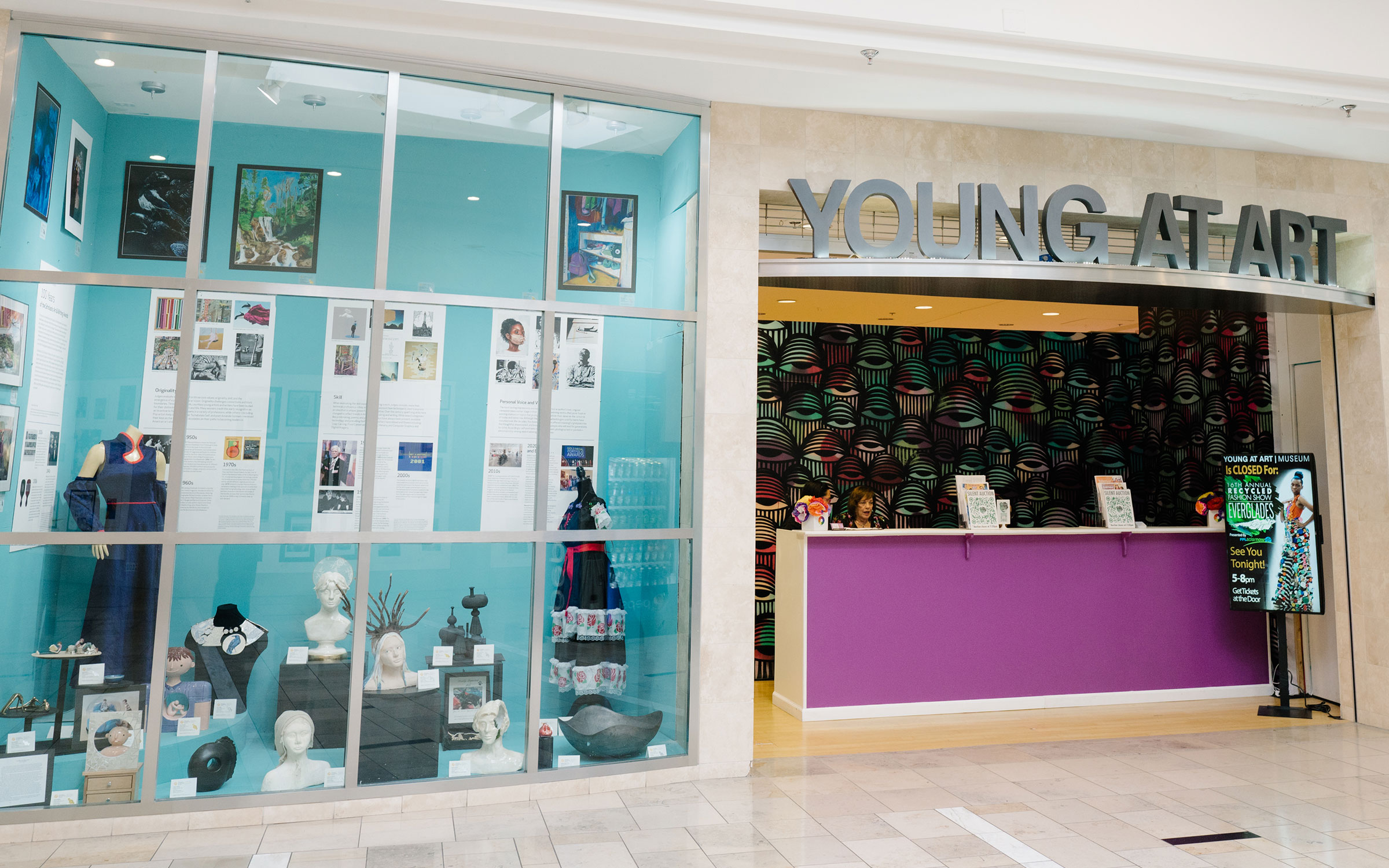 Gallery display window with artwork and sculptures, and a storefront with a purple counter and sign reading 'YOUNG ART'.