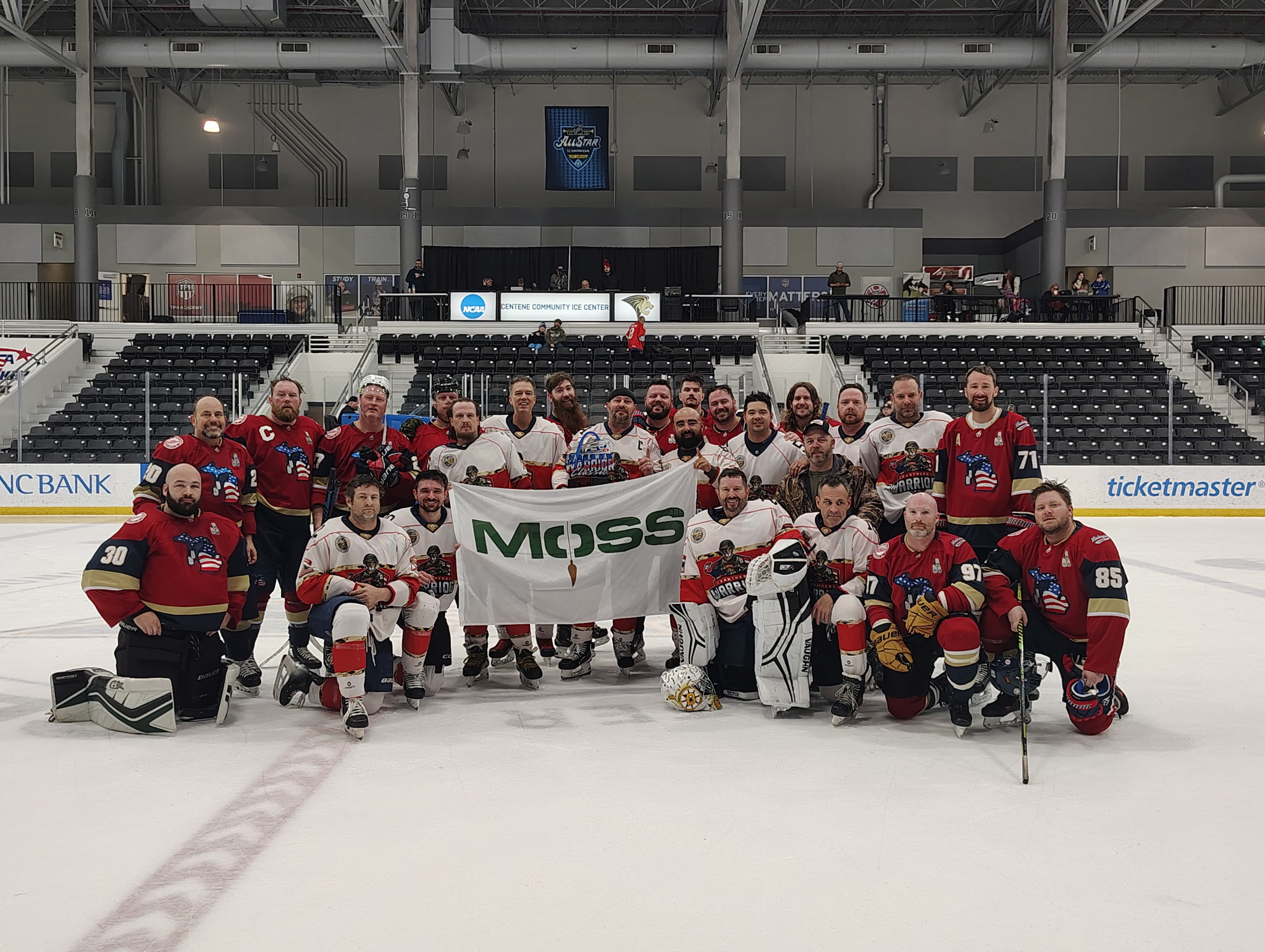 Ice hockey team and staff pose on ice holding a Moss banner in an arena.