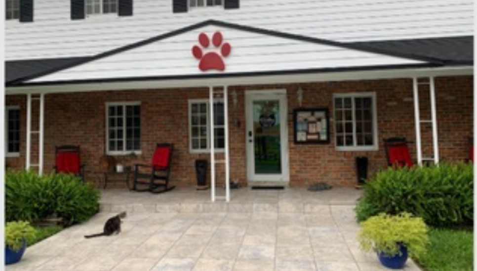 Brick building with a red paw print sign, benches, and potted plants outside.