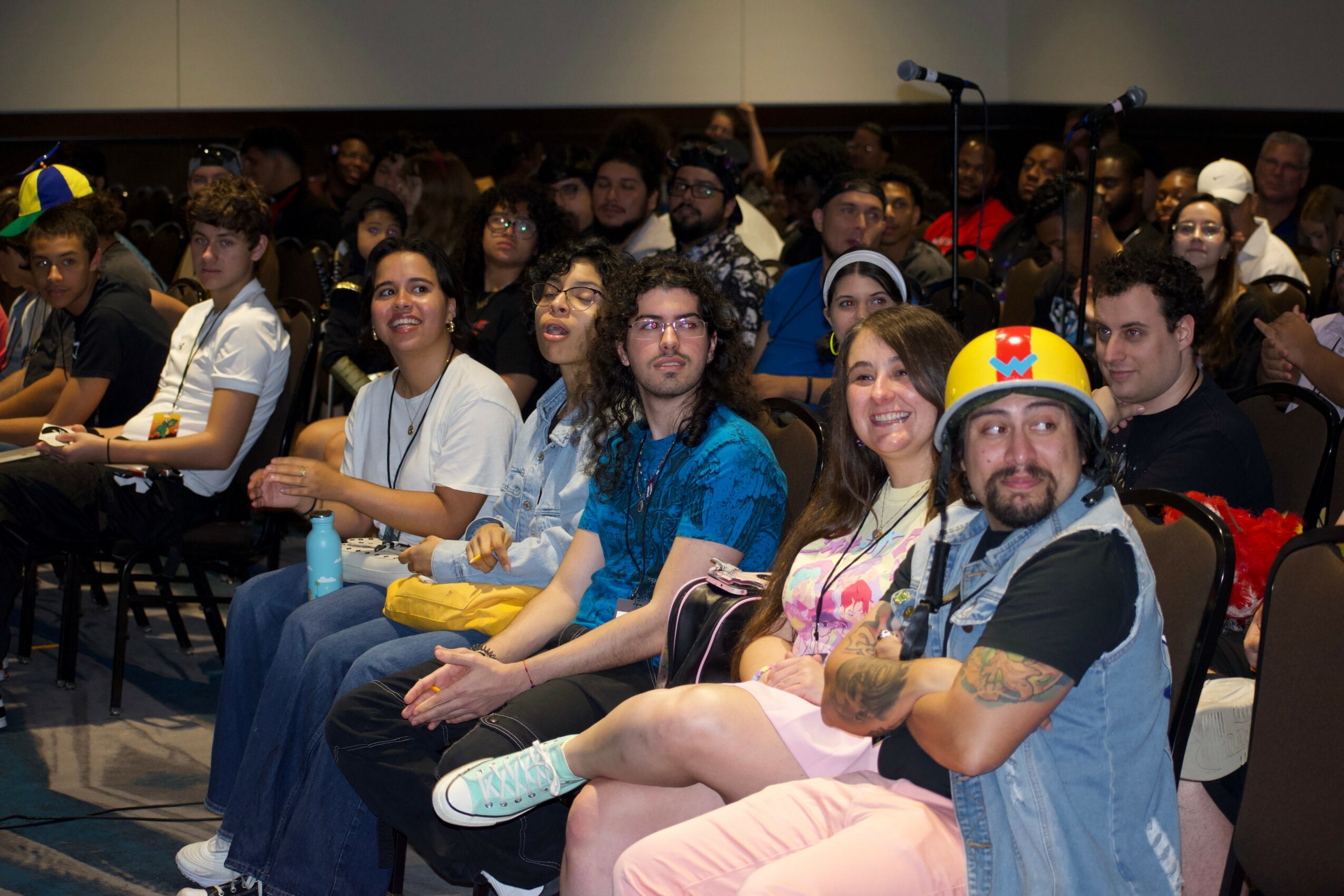 Audience seated in a conference room, some smiling, some wearing casual clothing, with a man in a firefighter costume in the front.