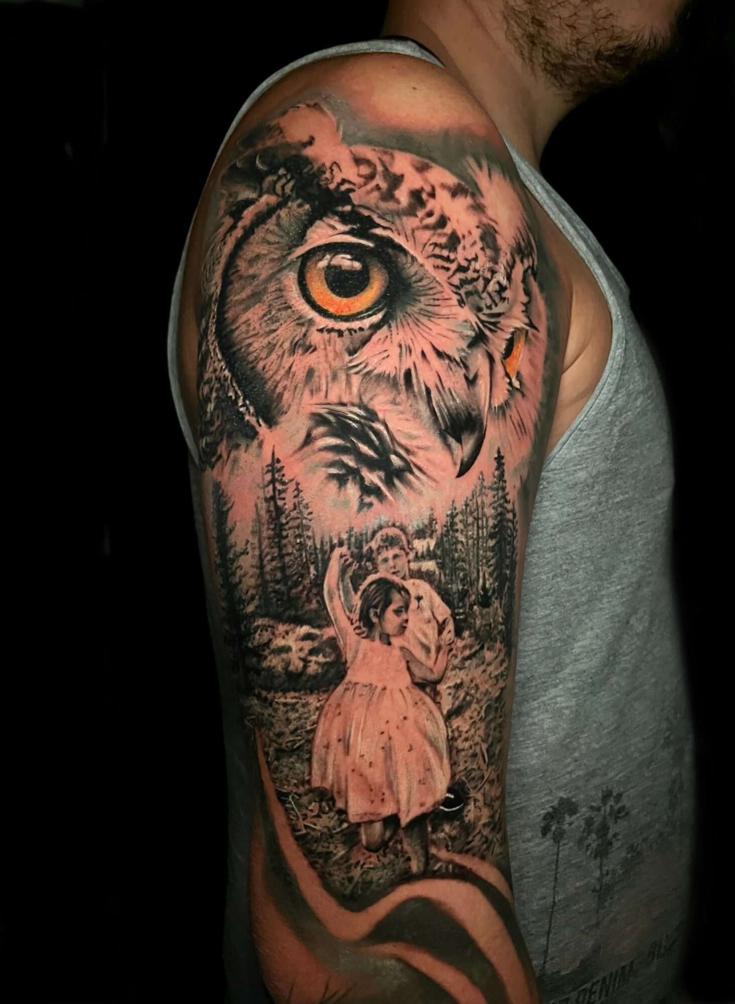 Tattoo of a tiger's face and eye, with a girl in a dress standing in a forest scene.