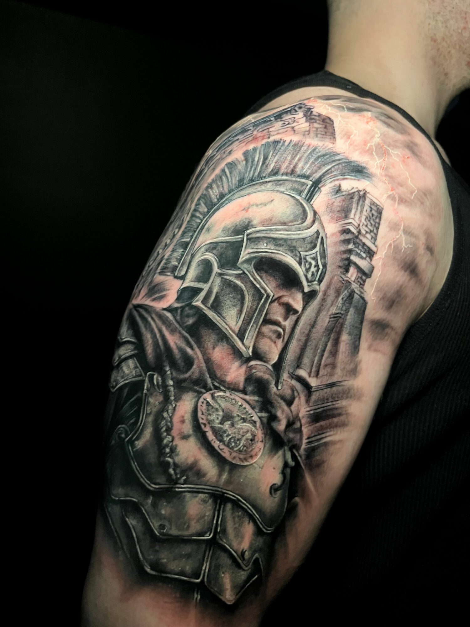 Black and gray tattoo of a soldier wearing a helmet and armor on upper arm.