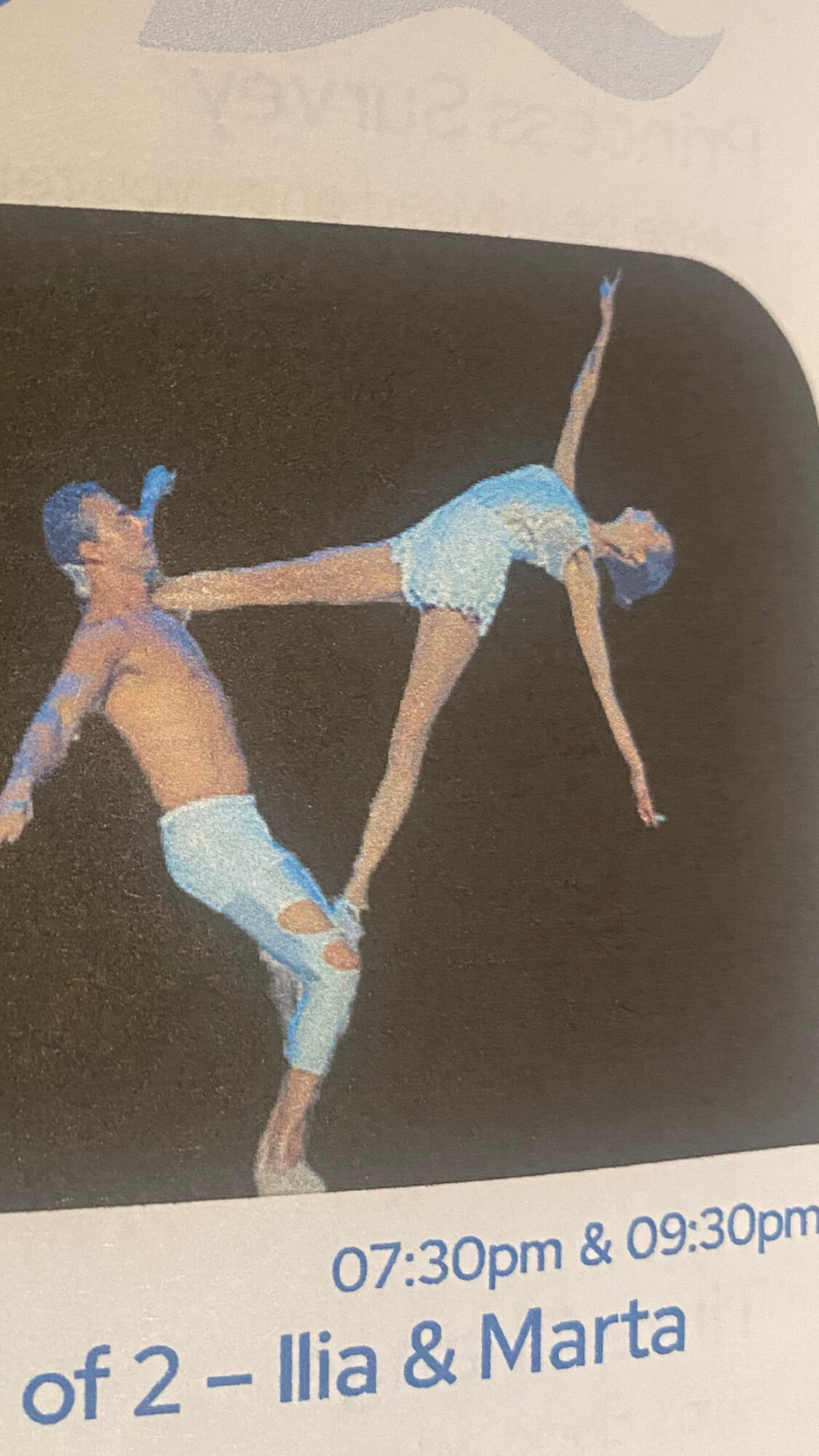 Two figure skaters perform a lift, one upside down with arms extended, the other supporting with arms and legs.