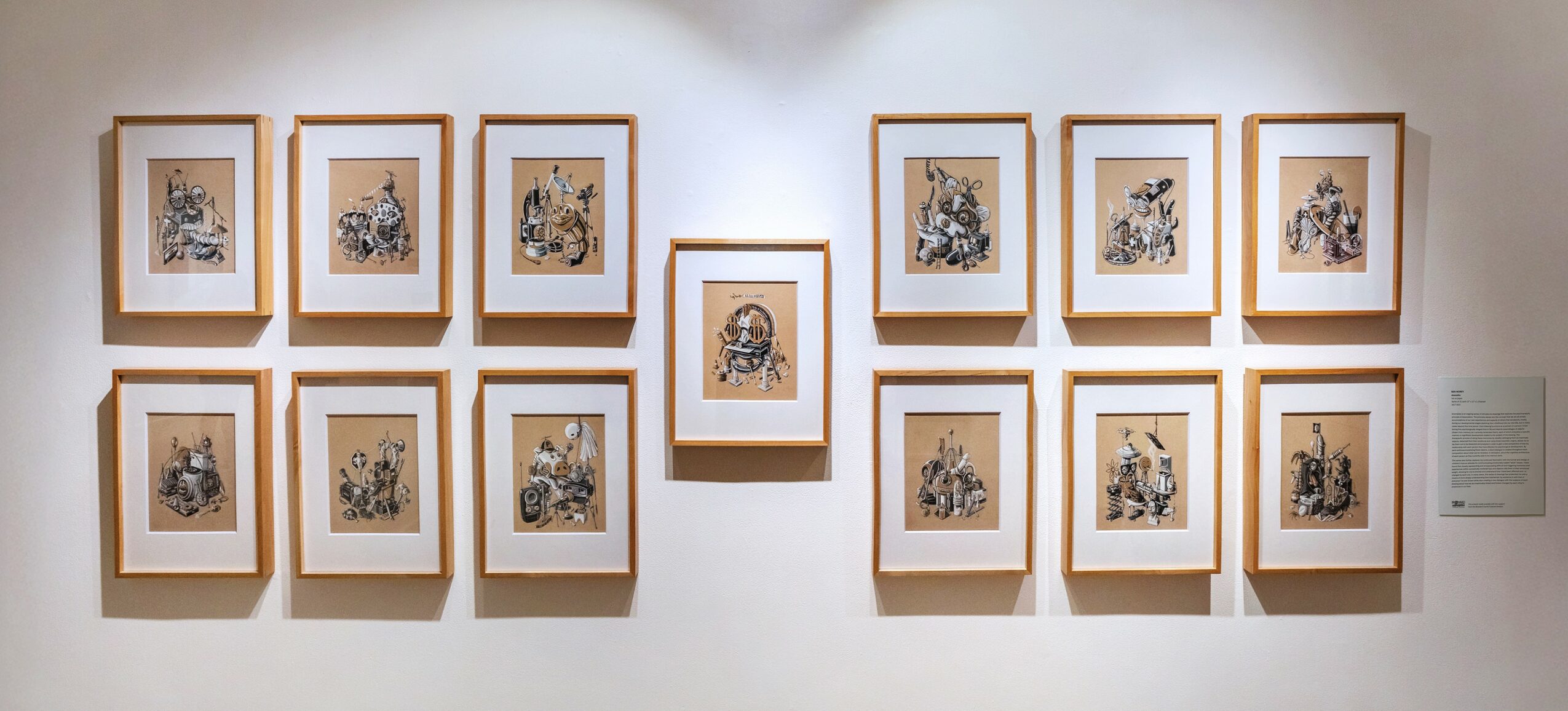 Gallery wall with framed artwork arranged in two rows, with a central piece, on a white wall.