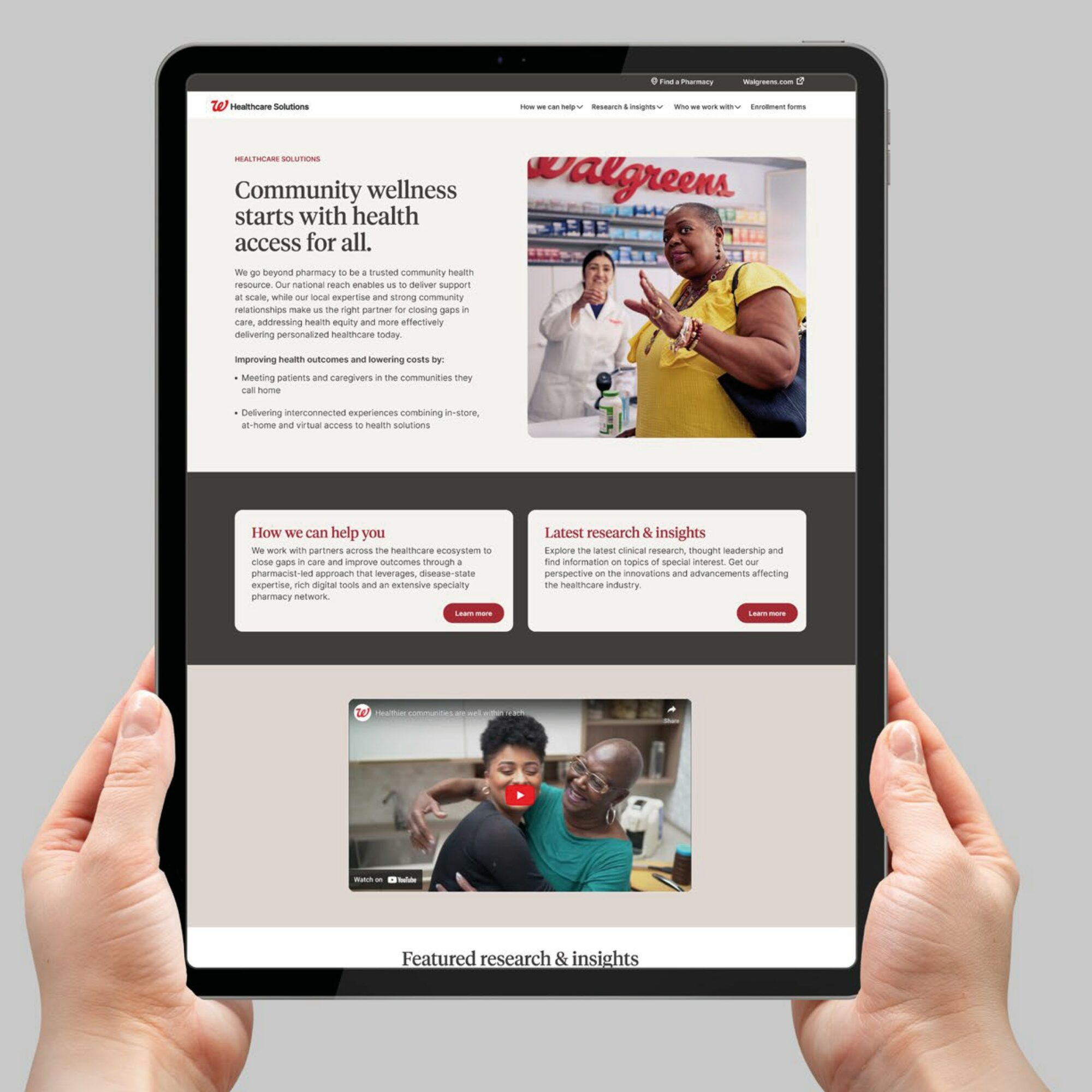 Person holding a tablet displaying a Walgreens webpage about community wellness and health access, with images of people and research sections.
