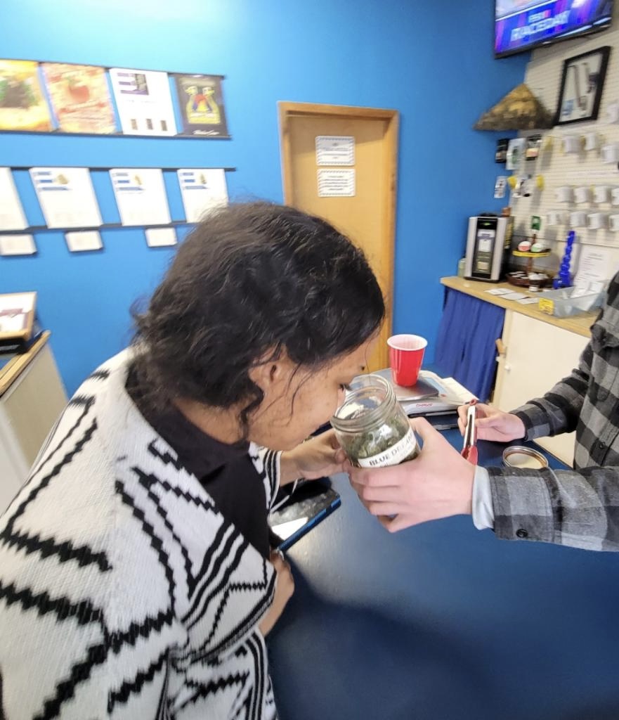Person receiving a jar from another person in a room with blue walls and various items on shelves
