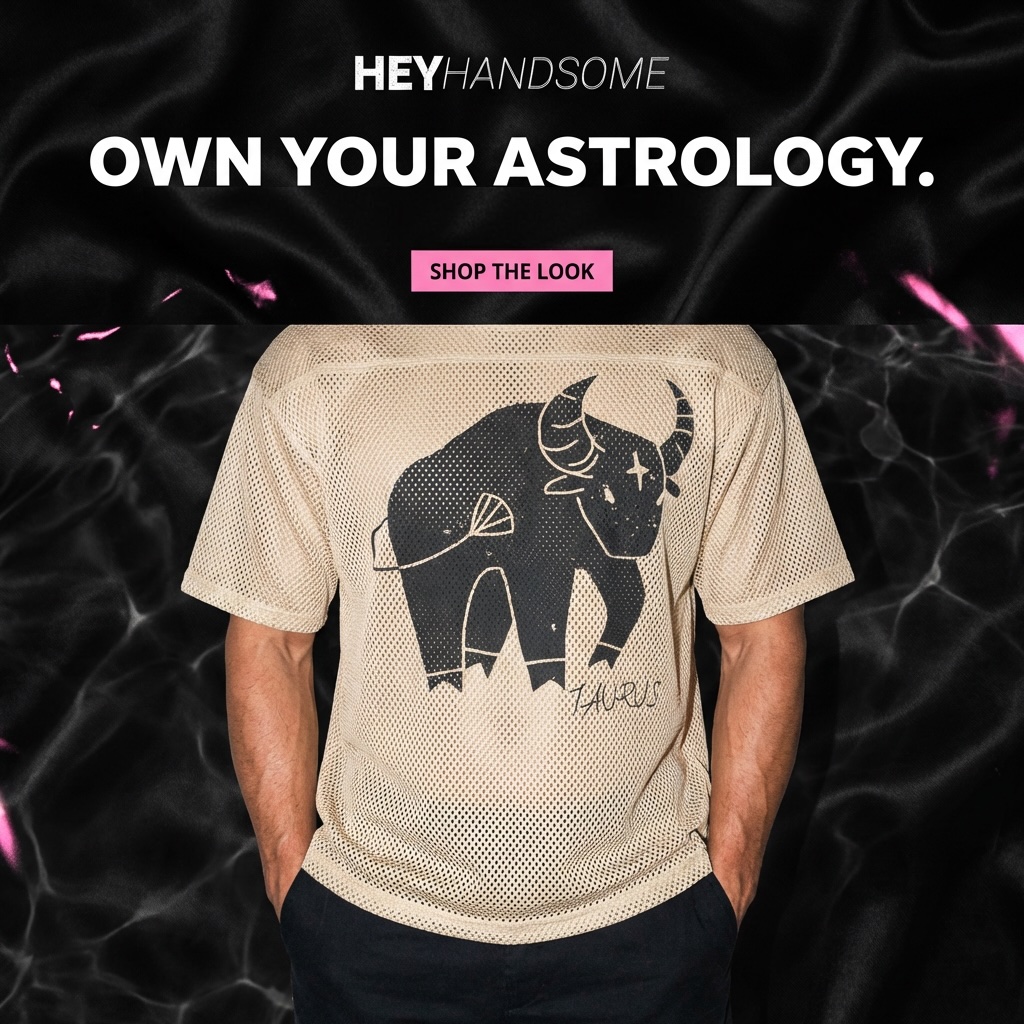Person wearing a beige T-shirt with a black bull and signature, standing against a dark background with pink accents.
