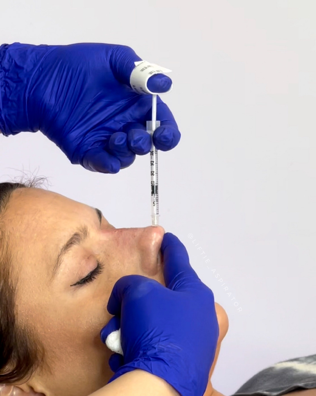 Person receiving nasal swab test, healthcare worker in blue gloves holding swab, close-up of face and testing procedure.