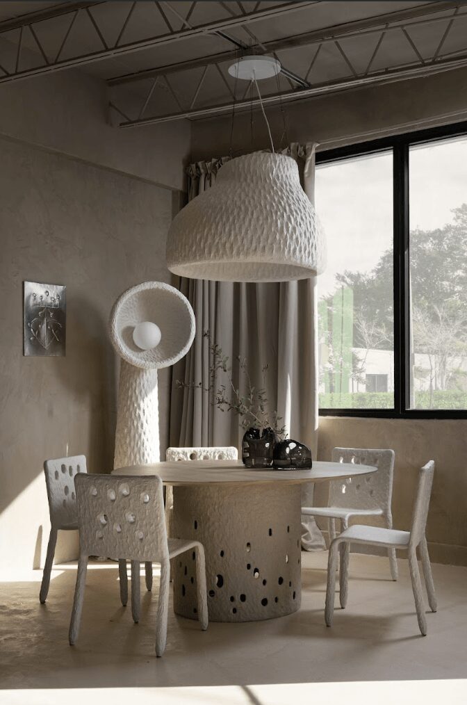Dining area with a round table, four chairs, large hanging lamp, and a window with curtains.