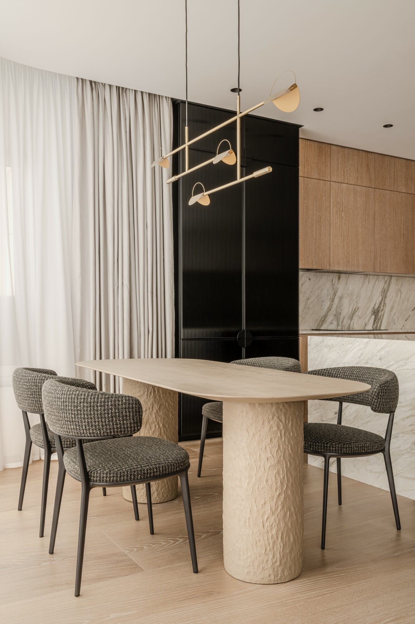 Dining area with a round table and four chairs, modern decor, black and wood accents, and a pendant light fixture.