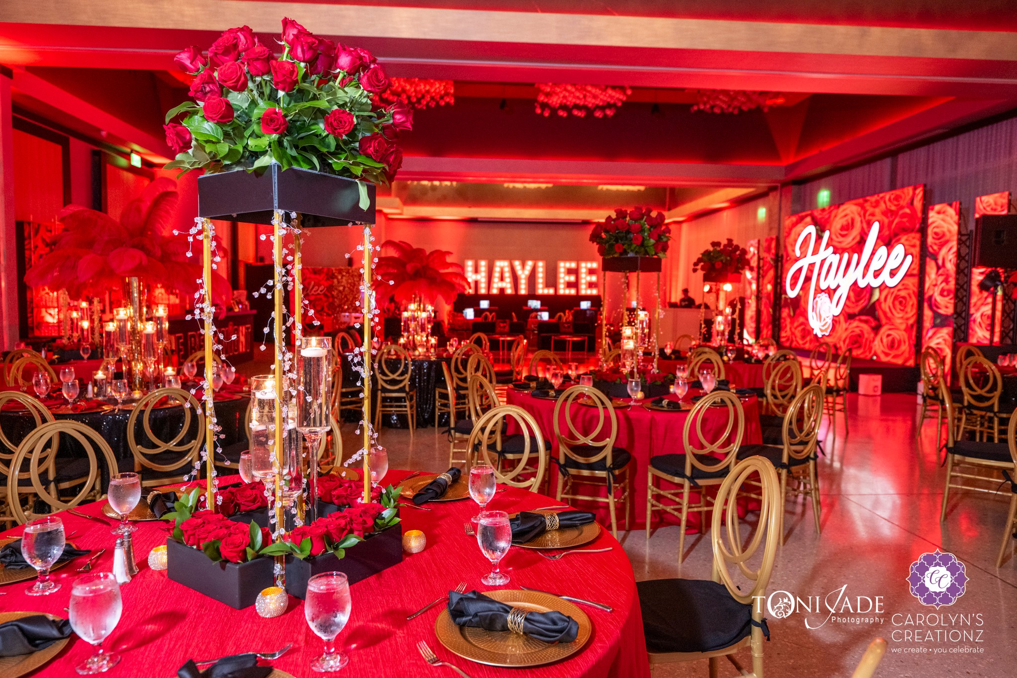 Event space decorated with red and pink flowers, tables with red tablecloths, and illuminated signs reading 'HAYLEE' and 'Haplee'.