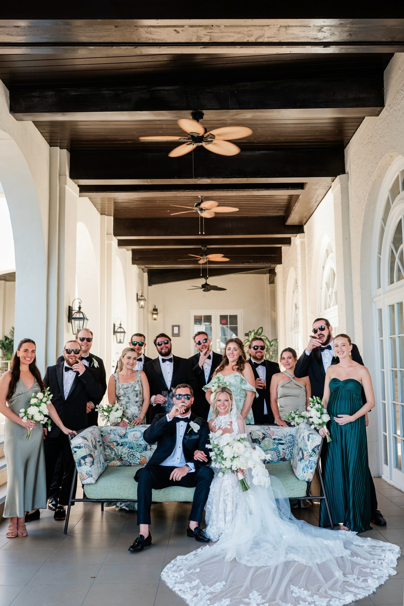 Group of people, including bride and groom, in a bright indoor space with high ceilings and wooden beams.