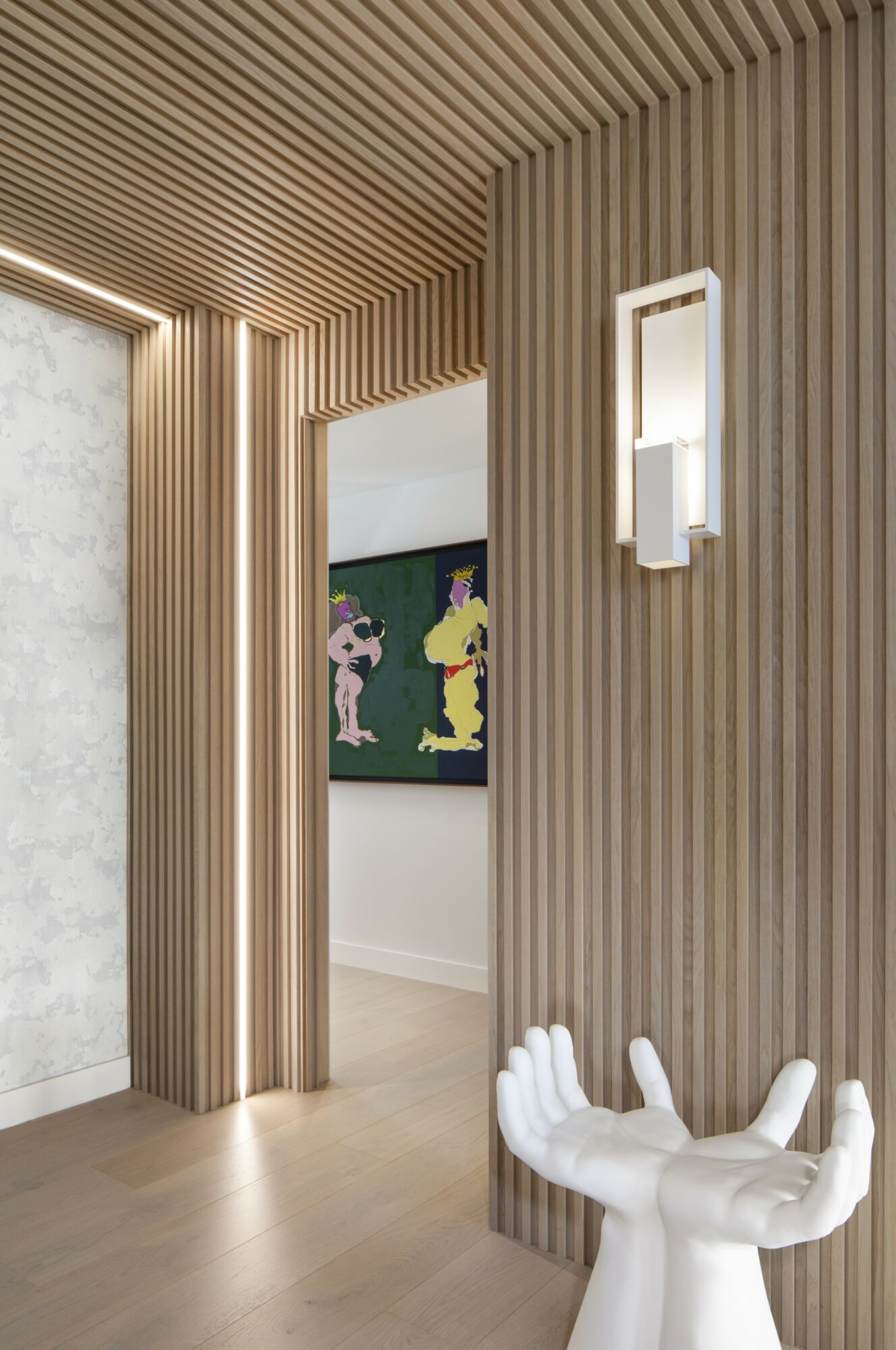 Interior space with wooden slat walls and ceiling, a wall-mounted light, and a white sculpture of hands in foreground.