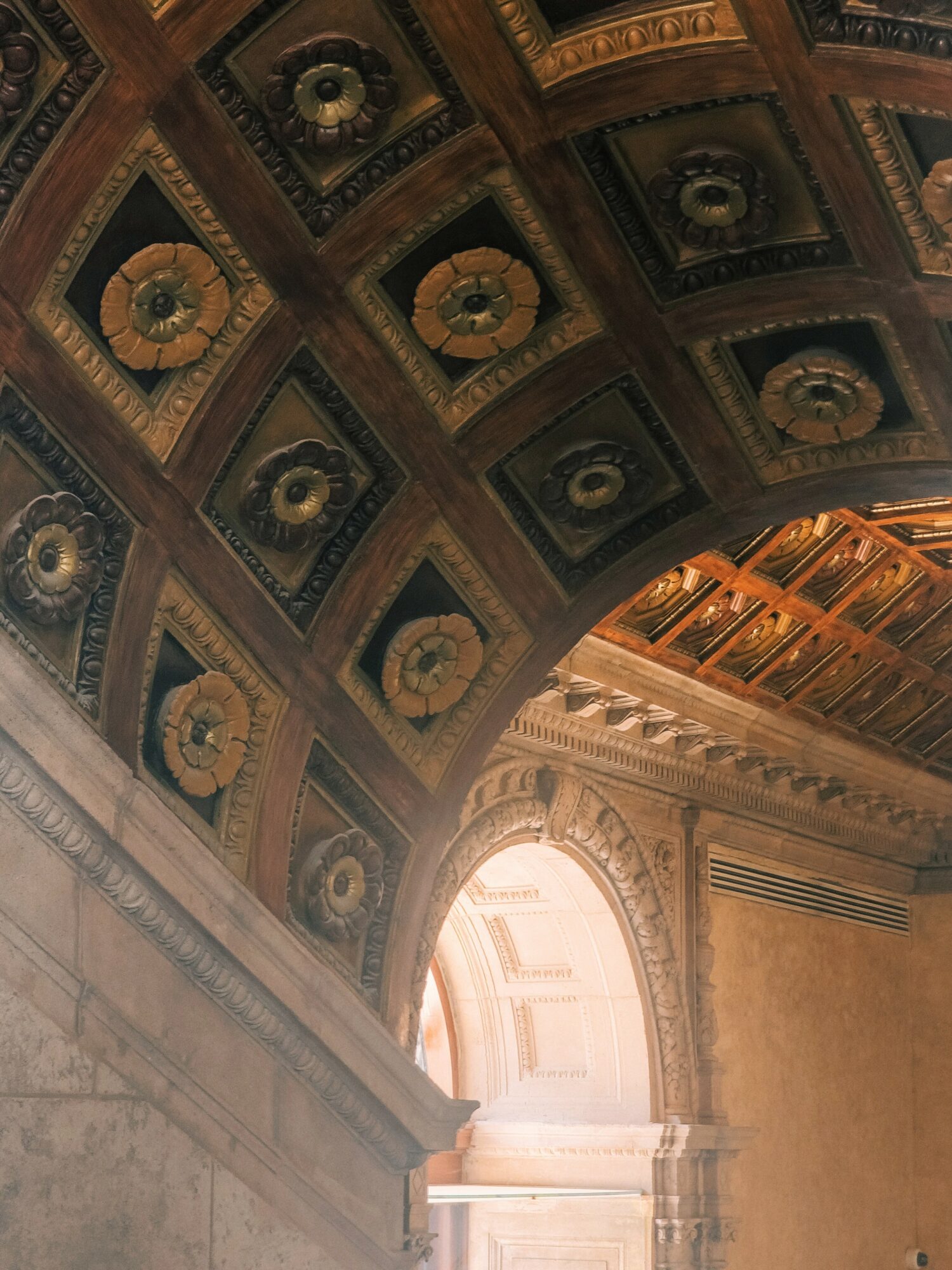 Decorative ceiling with ornate square patterns and a bright arched window illuminating the interior.