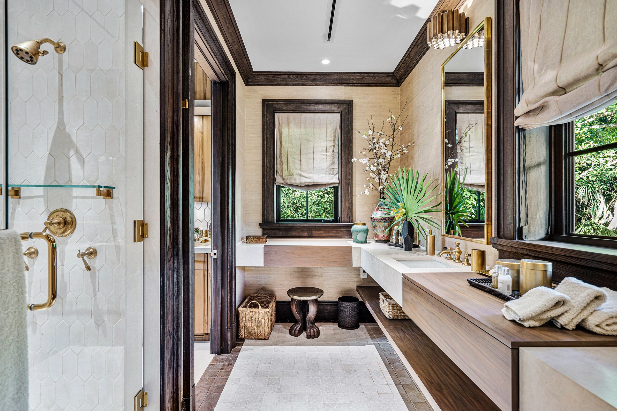 Bathroom with window, vanity, mirror, plants, towels, and decorative items, with a marble shower area on the left.