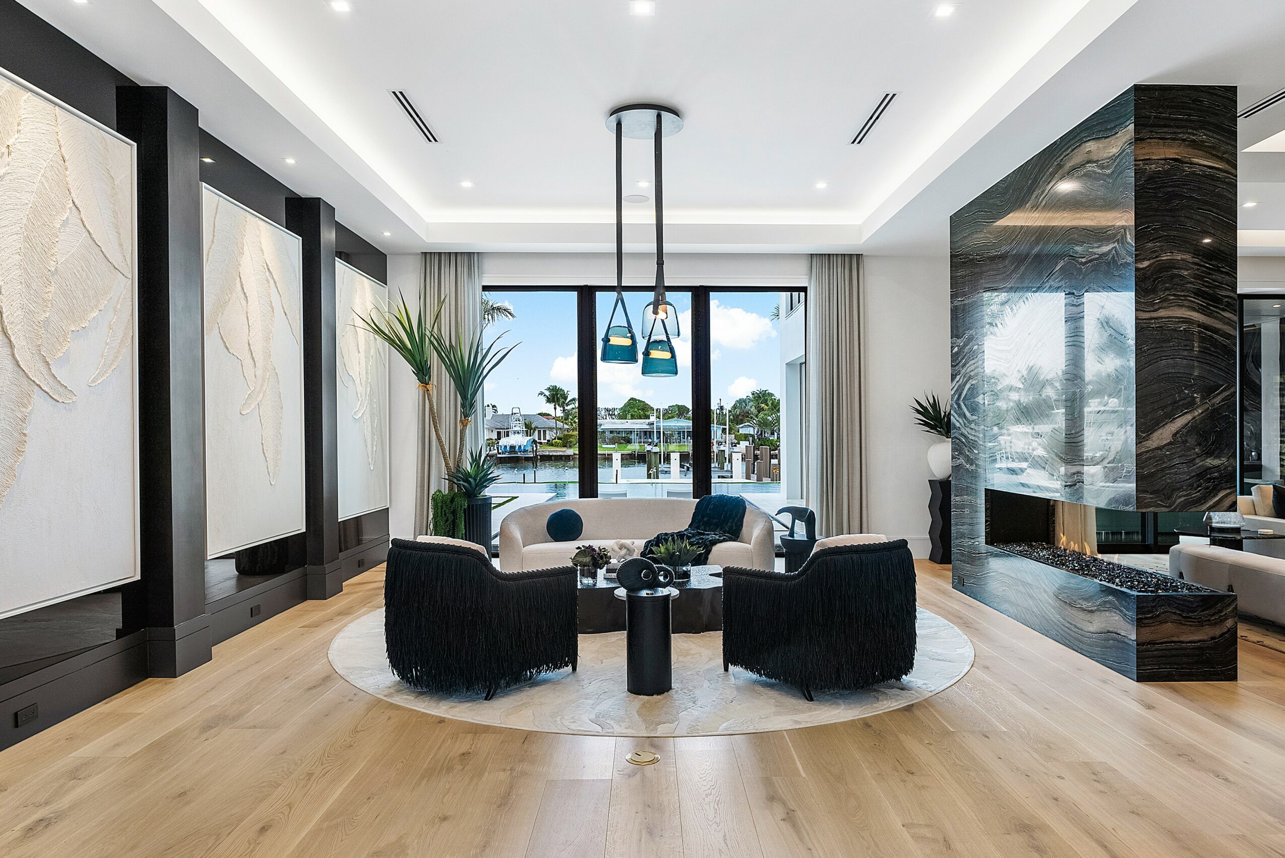 Modern living room with four black chairs around a small table, large window, and decorative wall panels.