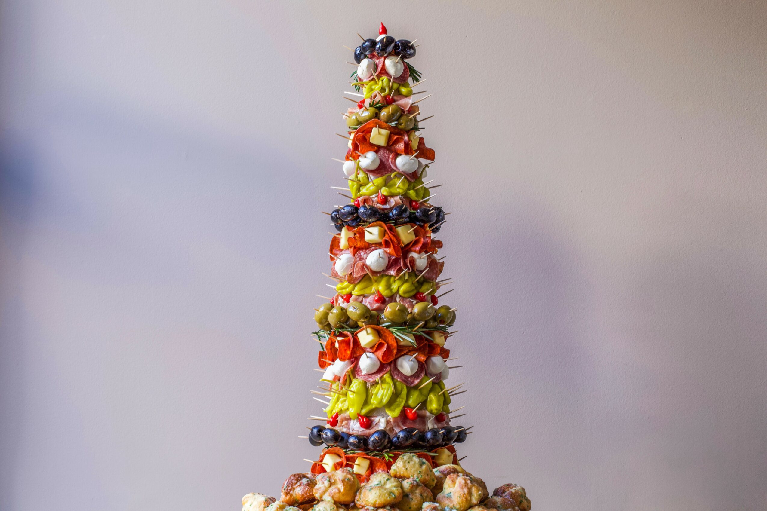 A tall, cone-shaped Christmas tree made of various candies and treats, decorated with ribbons and ornaments.
