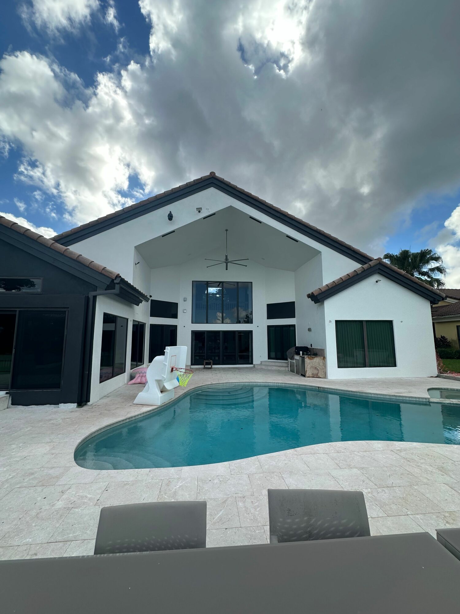 Modern house with a swimming pool, white exterior, and large windows, under a cloudy sky.