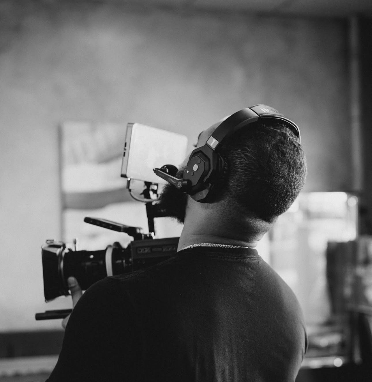 Person wearing headphones operating a camera in a room with a blurred background.